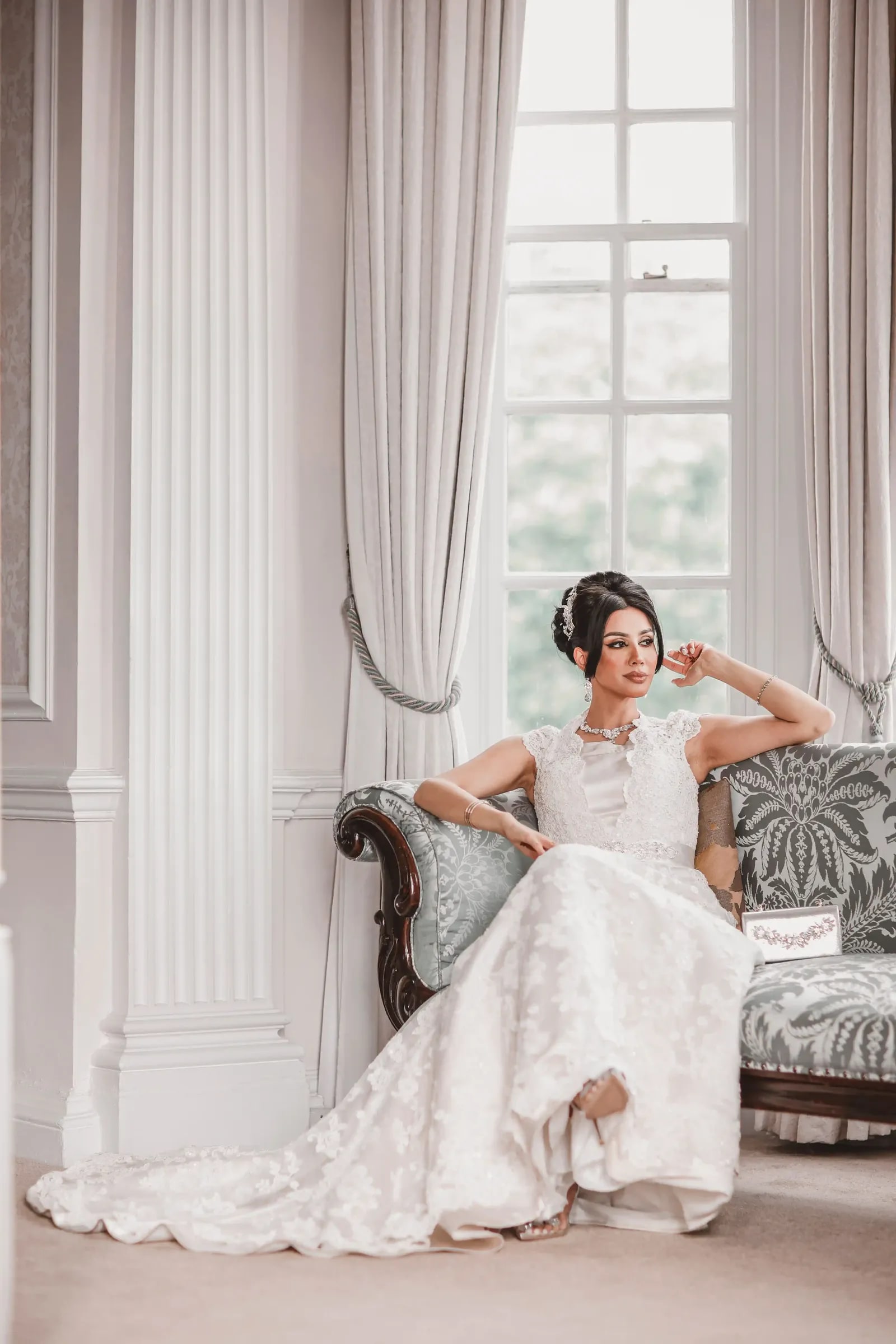 Bride seated on the chaise longue between the columns, her train spread out