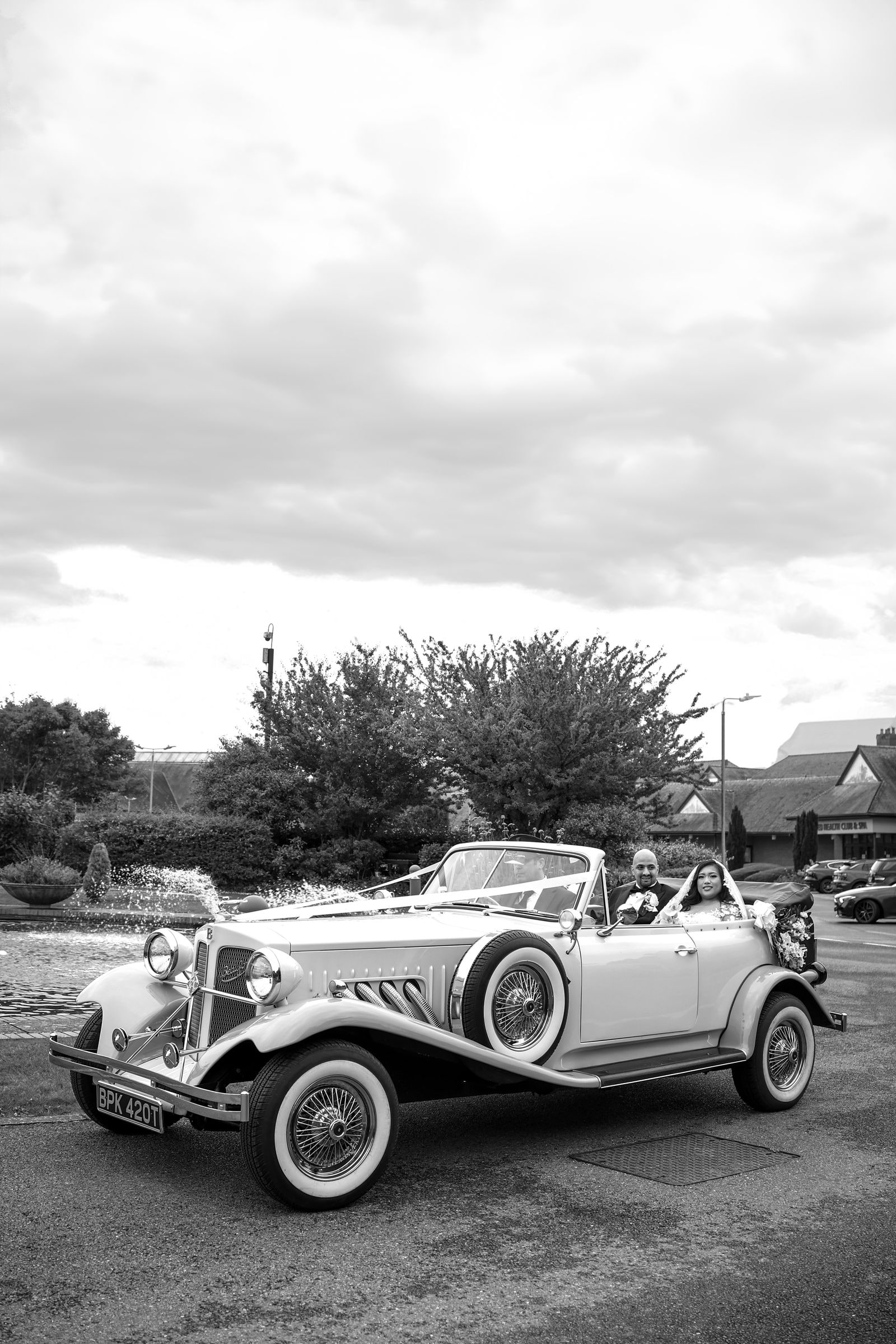 A vintage Beauford convertible waiting outside the venue, in black and white