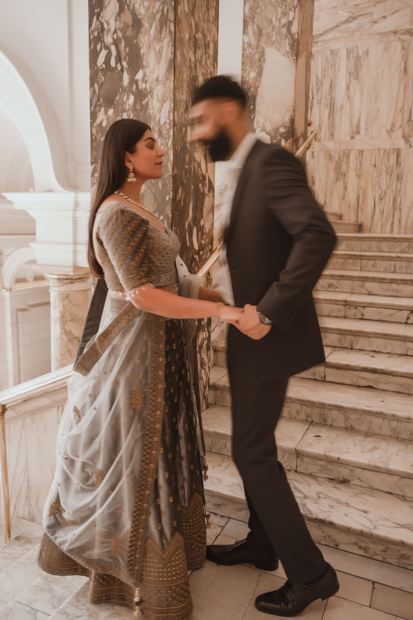 Couple turning together on the marble stairs, her dupatta swinging out