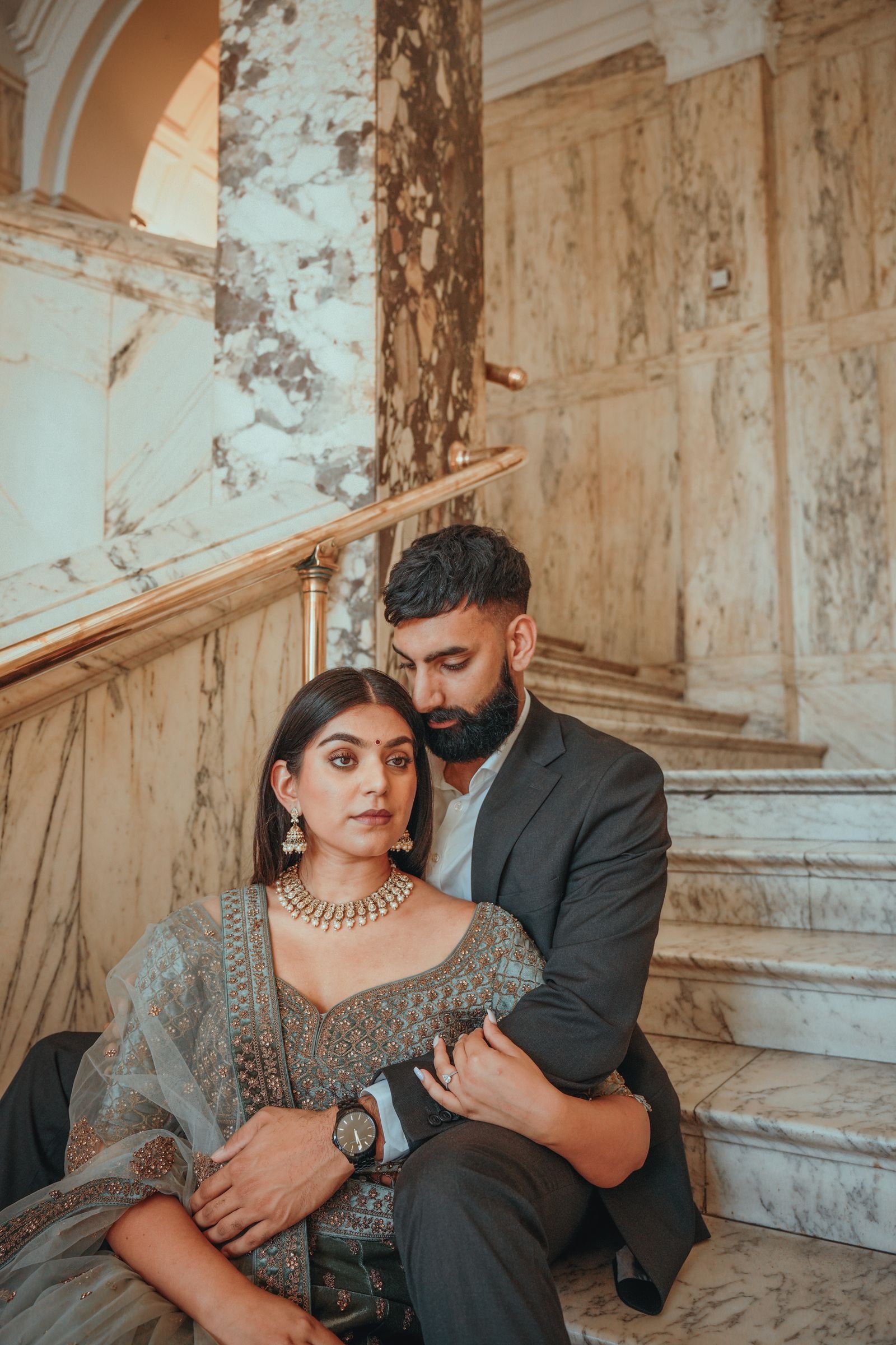 Couple seated together on the marble stairs, his arm around her