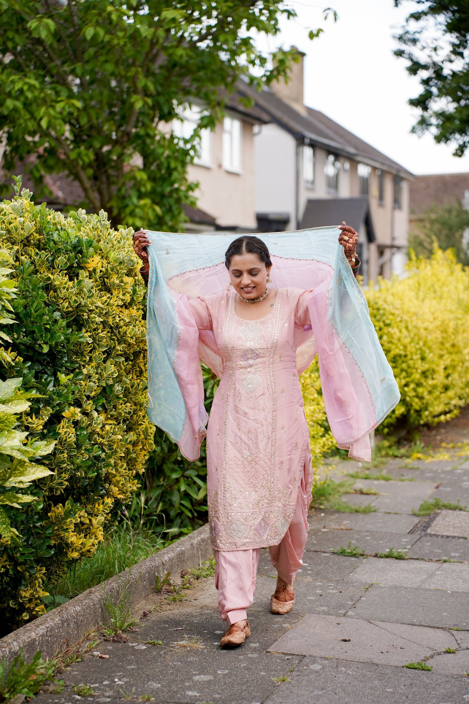 A woman walking a suburban path with a pale cloth held out behind her