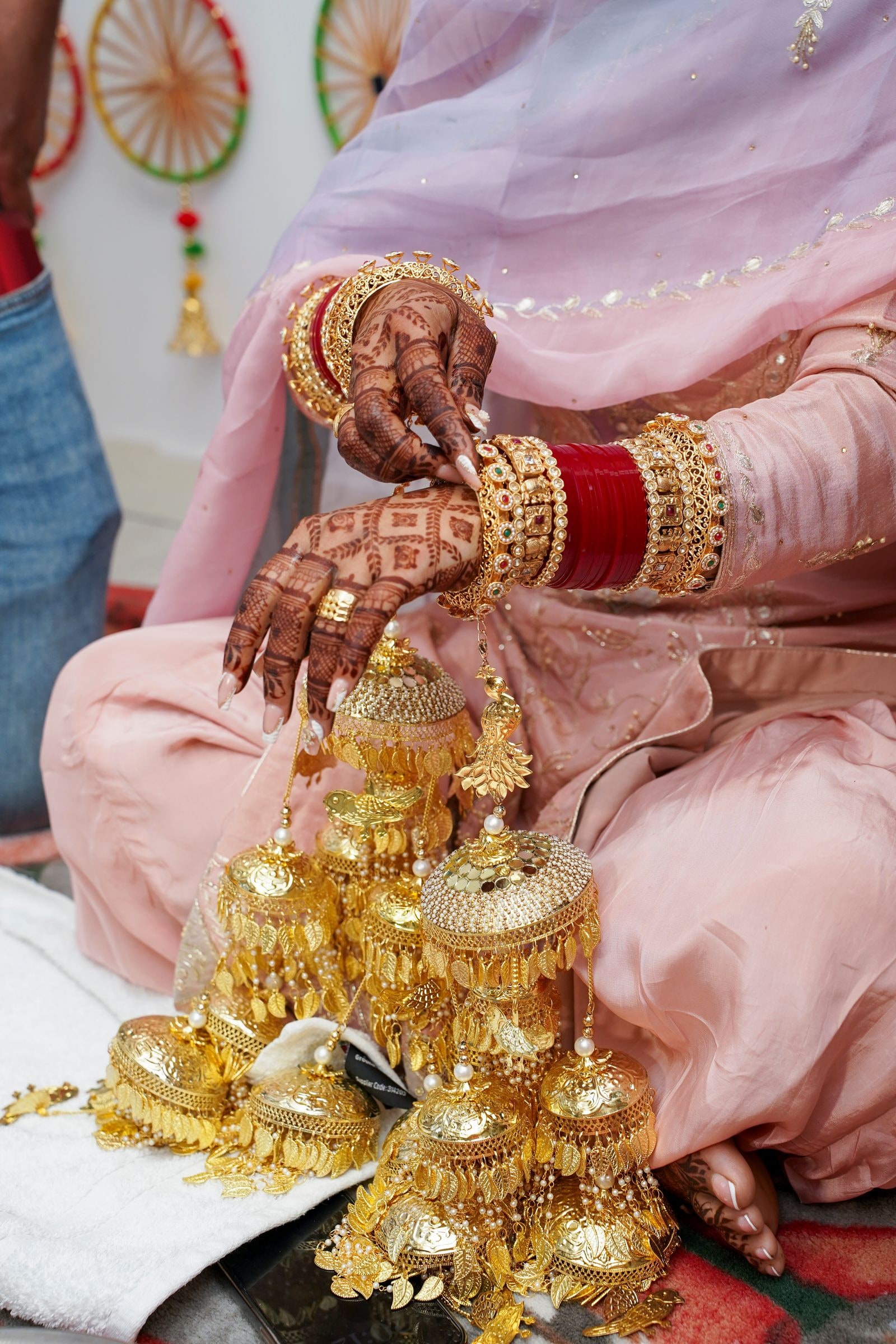 The bride's hennaed hands over a heap of gold kalire during the chura ceremony