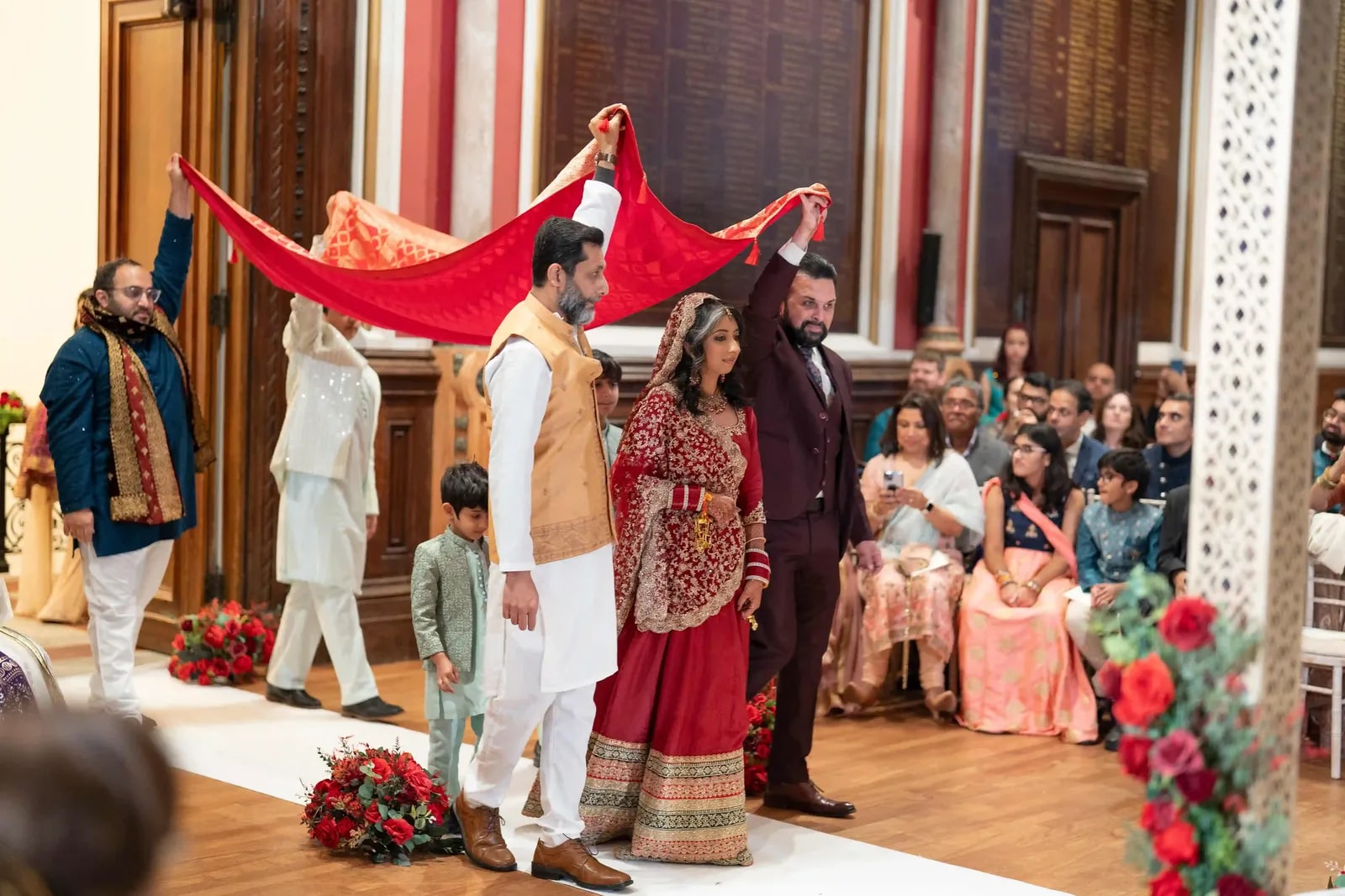 The bride walked in beneath a red cloth held over her by her family