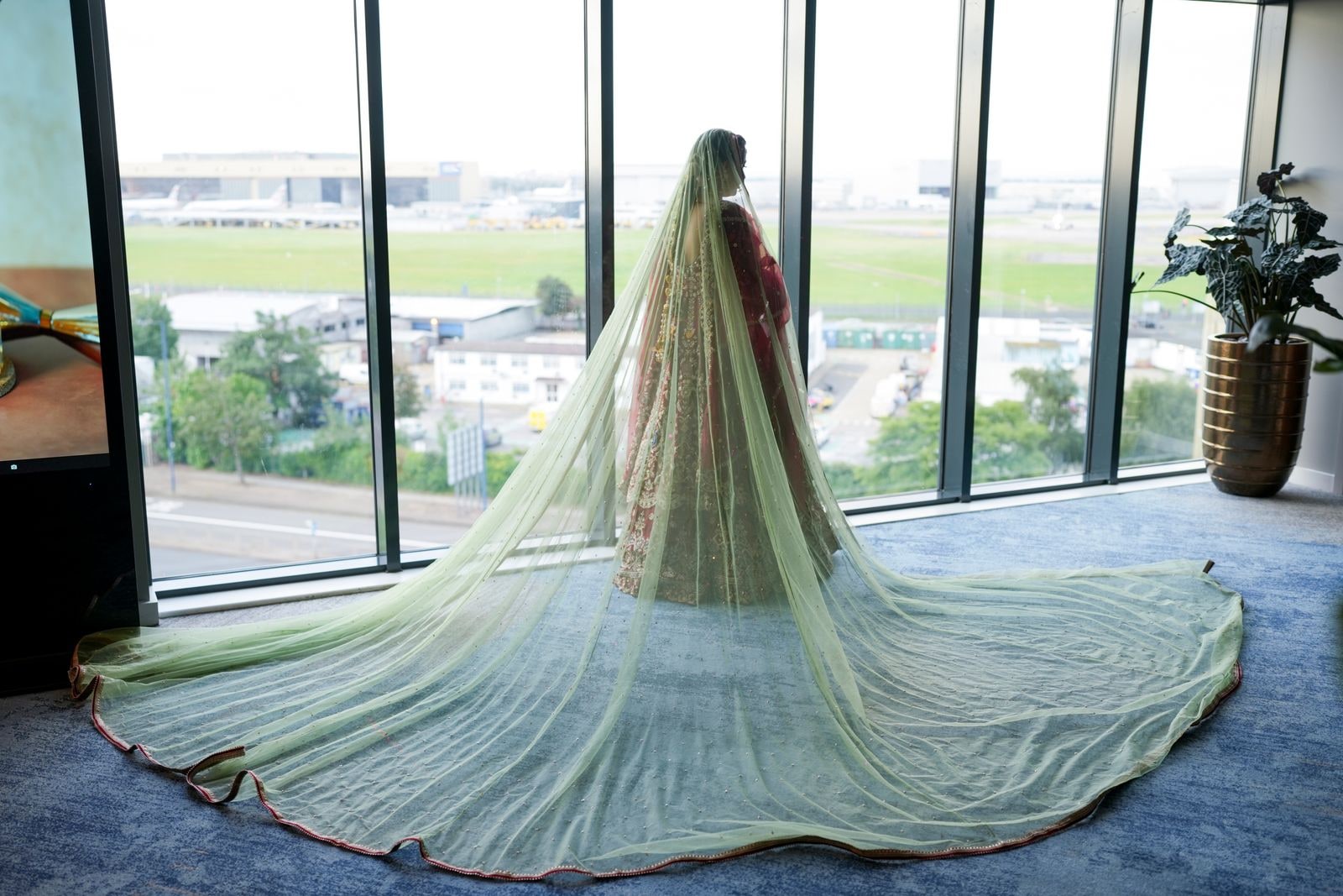 Bride seen from behind at a window, her pale green veil spread out across the floor