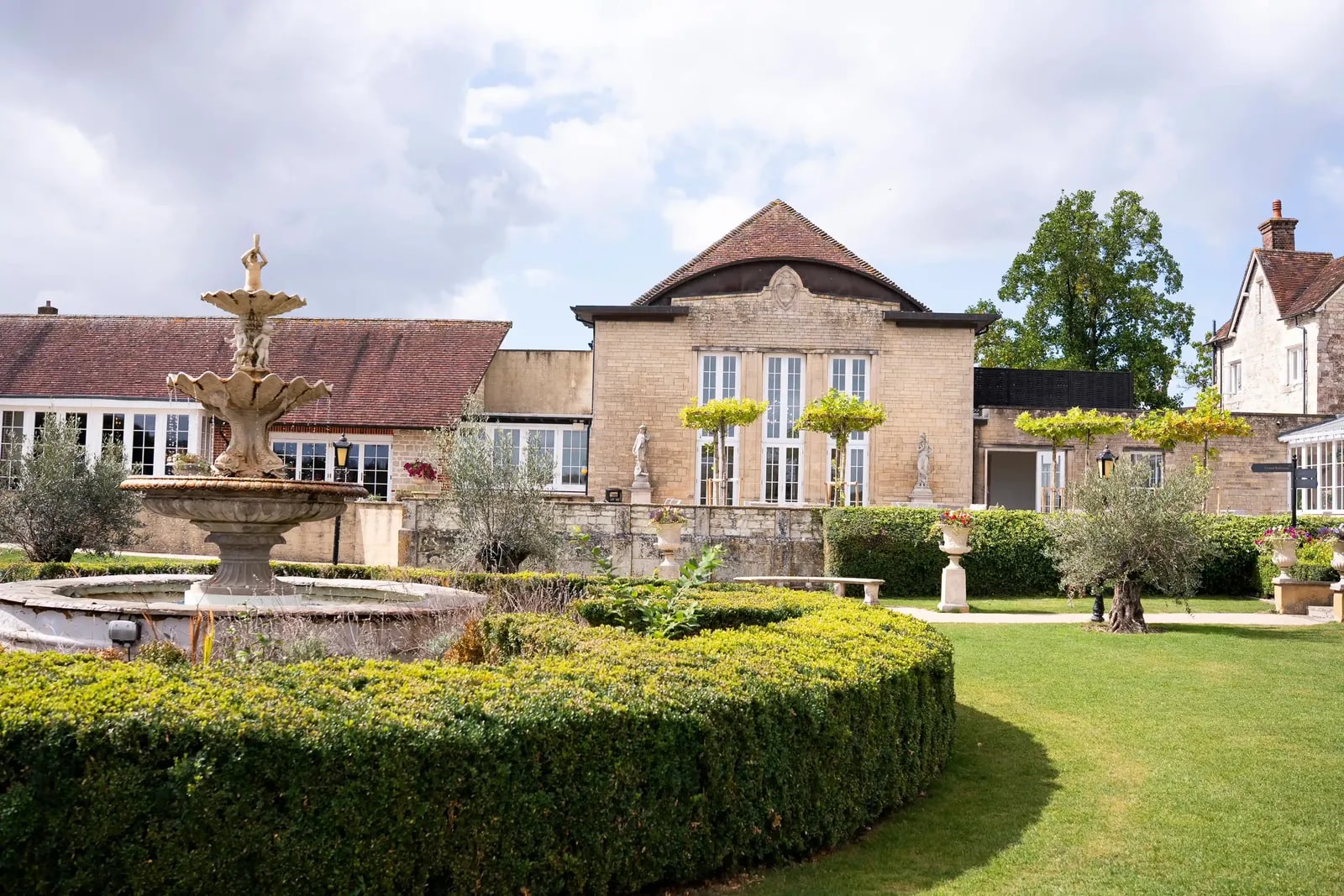 The fountain and formal garden at Froyle Park under a bright sky
