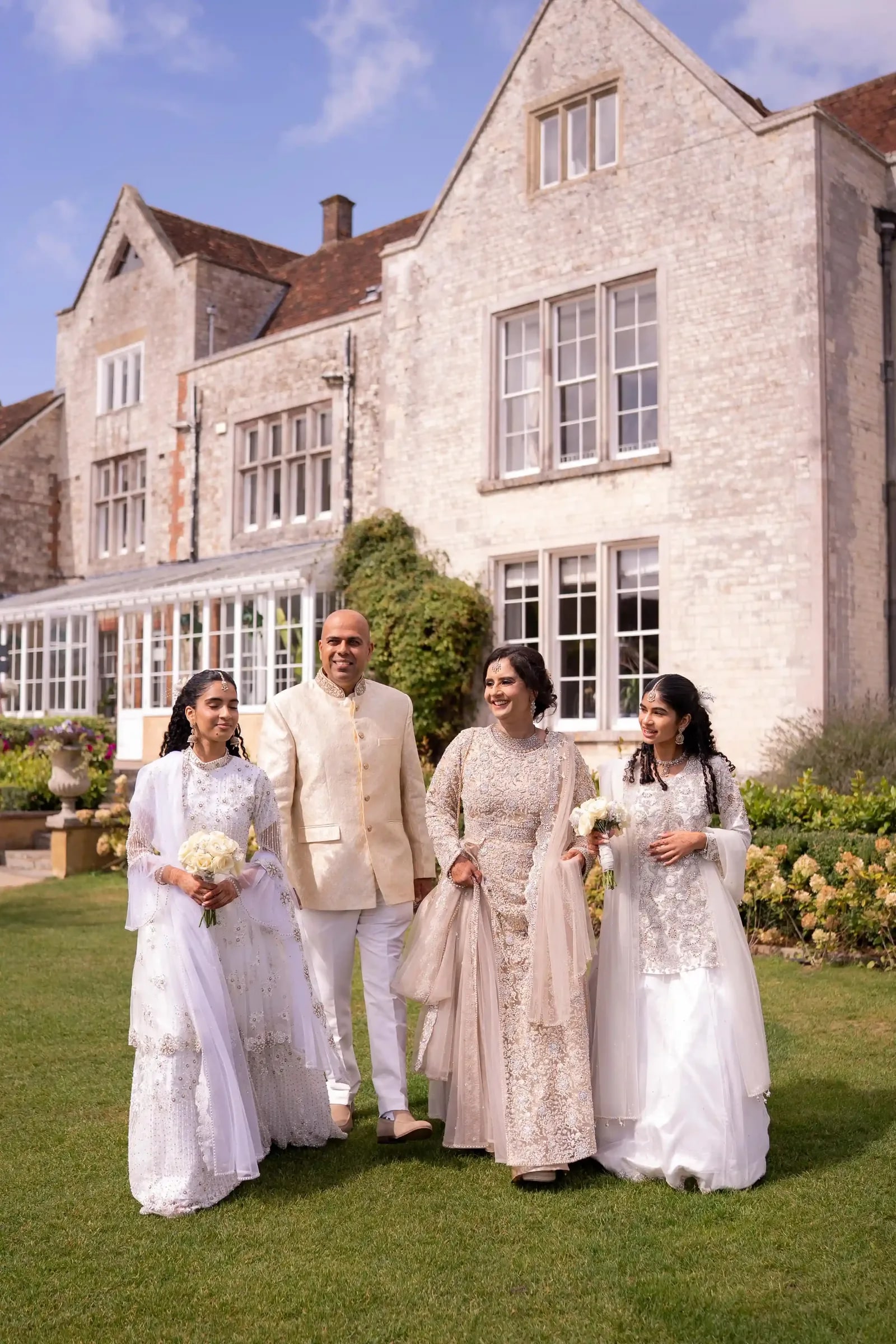 The bride's family in ivory walking together across the lawn