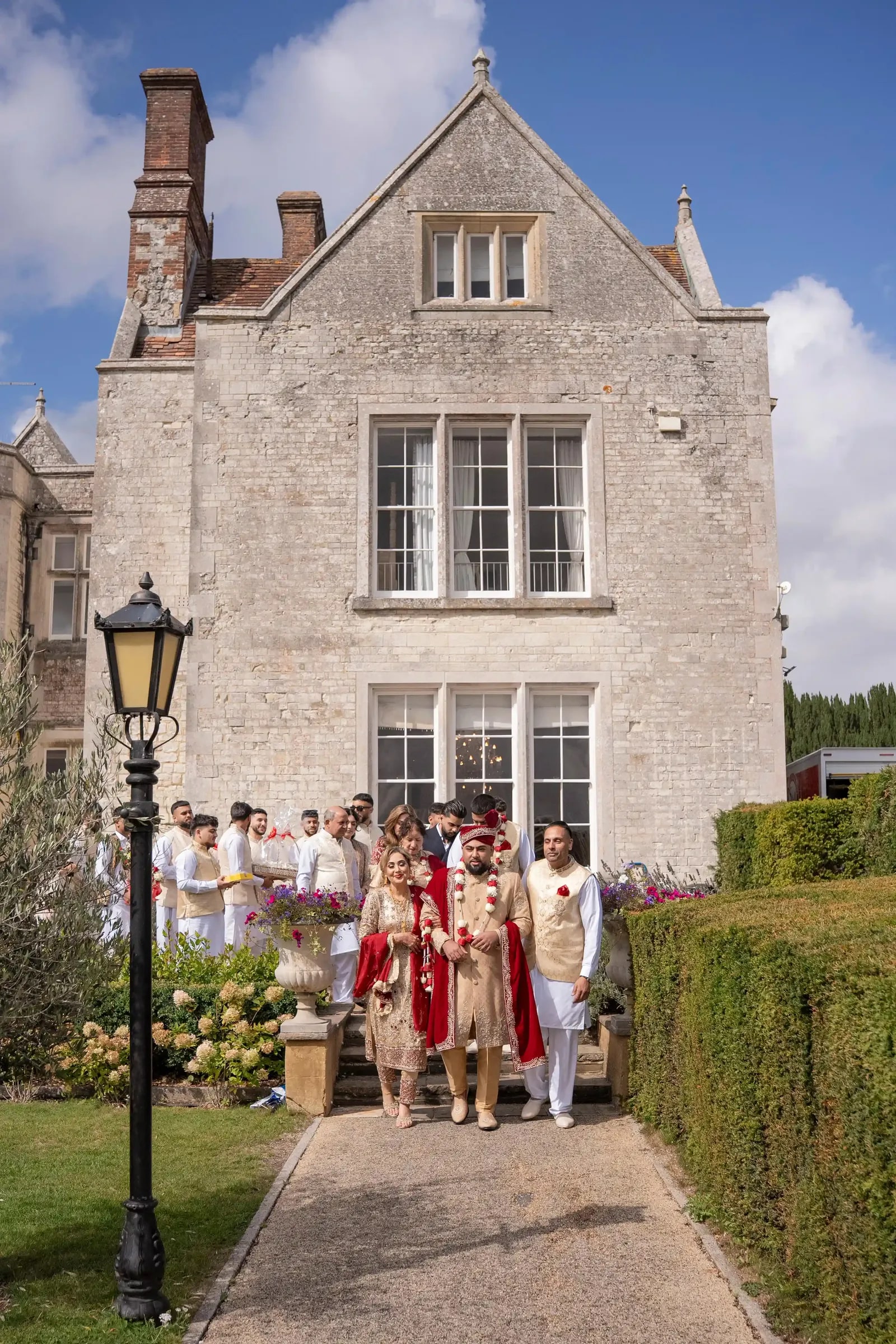 Groom walking down the path from the house with his party behind him