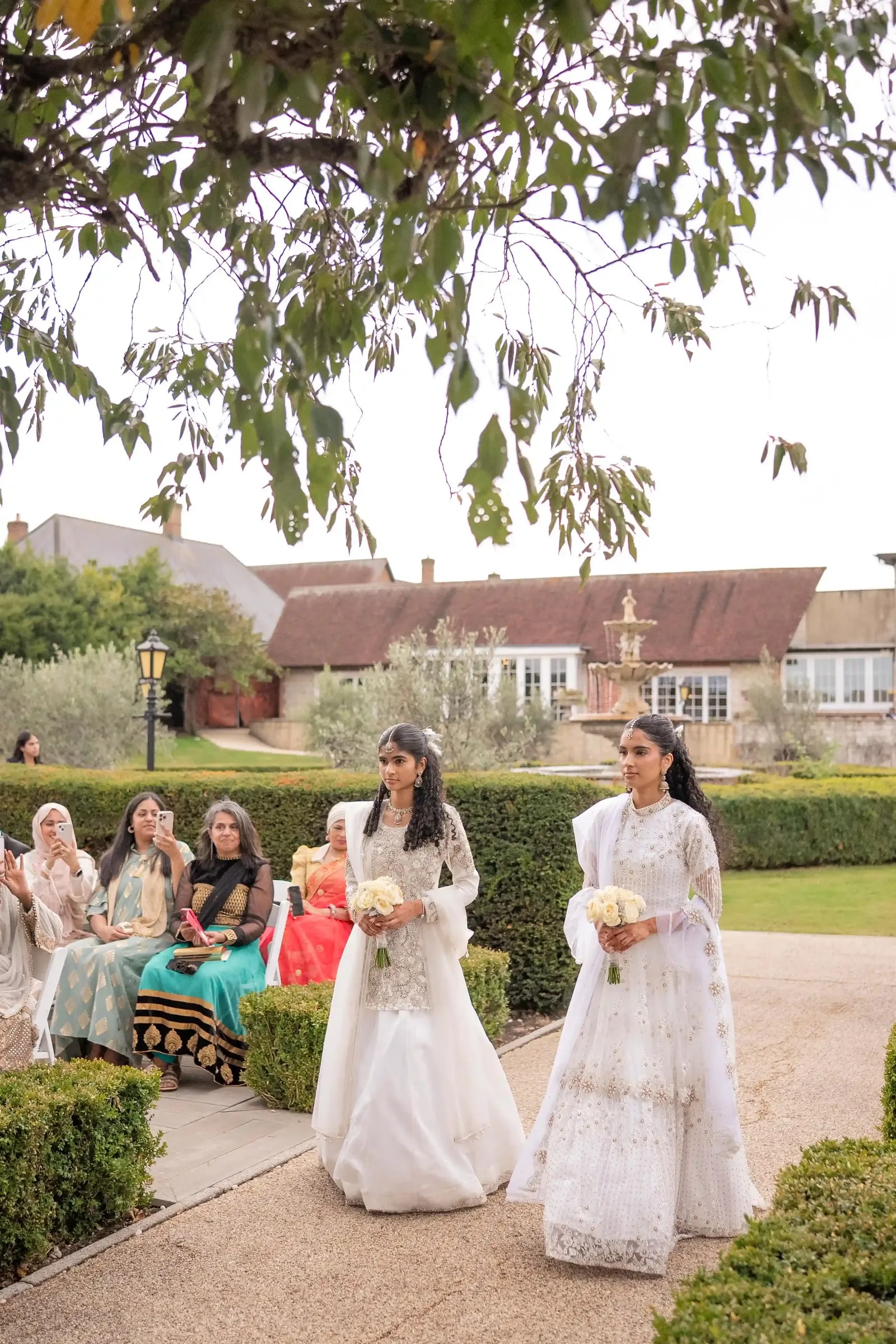 The bride's party walking the path past guests seated in the garden
