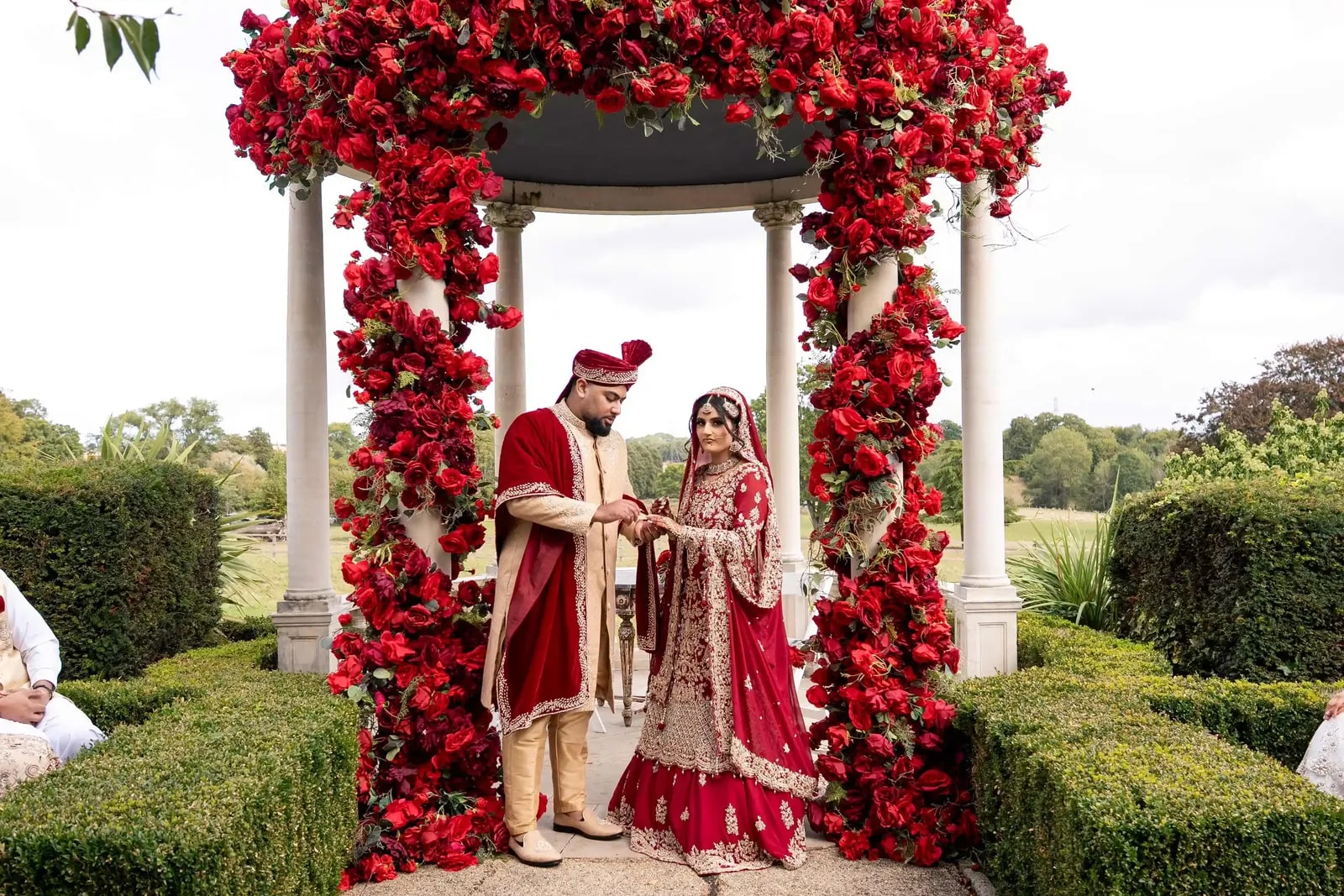 Bride and groom together under the red rose arch after the ceremony