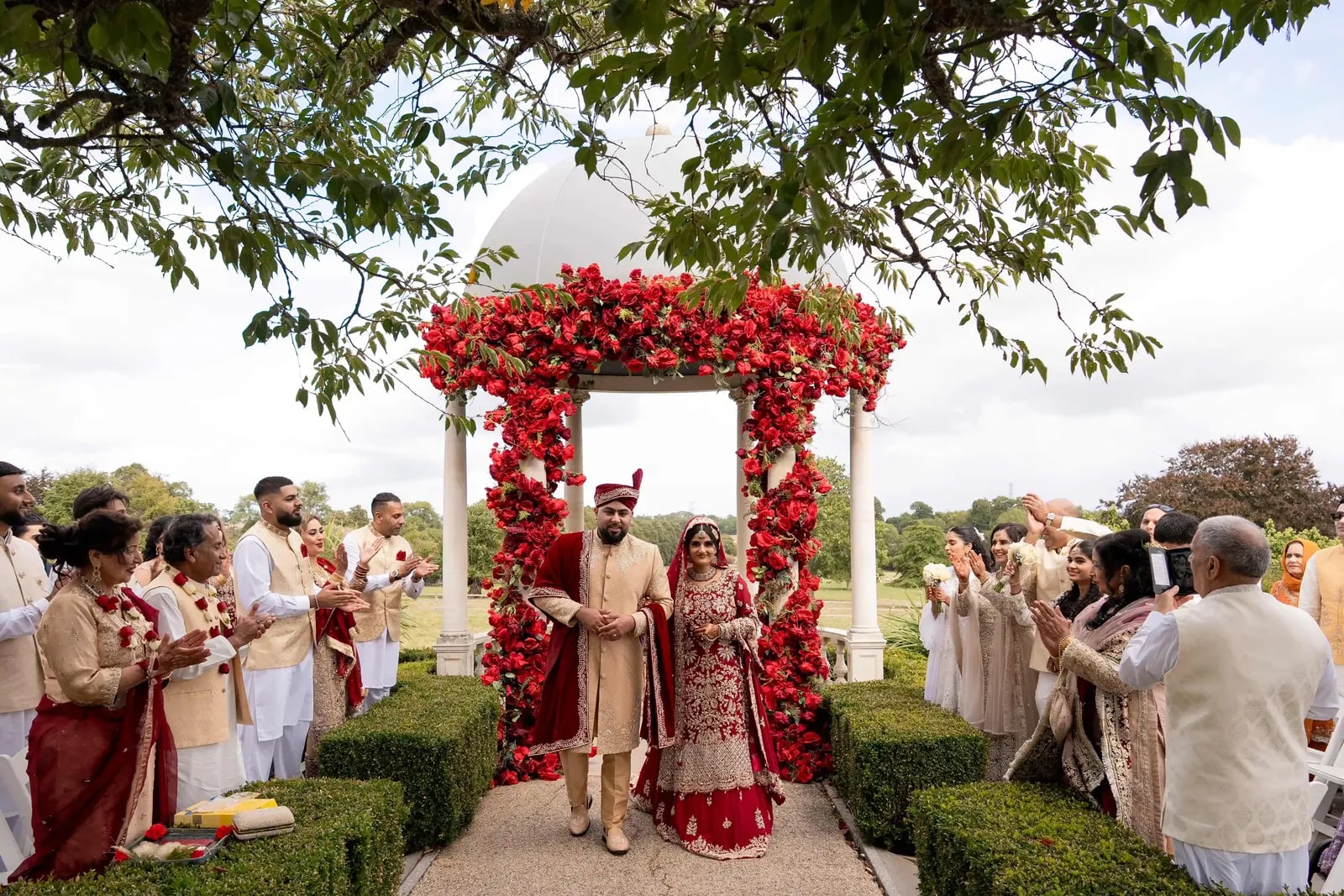 Couple walking out from the arch as guests applaud from both sides