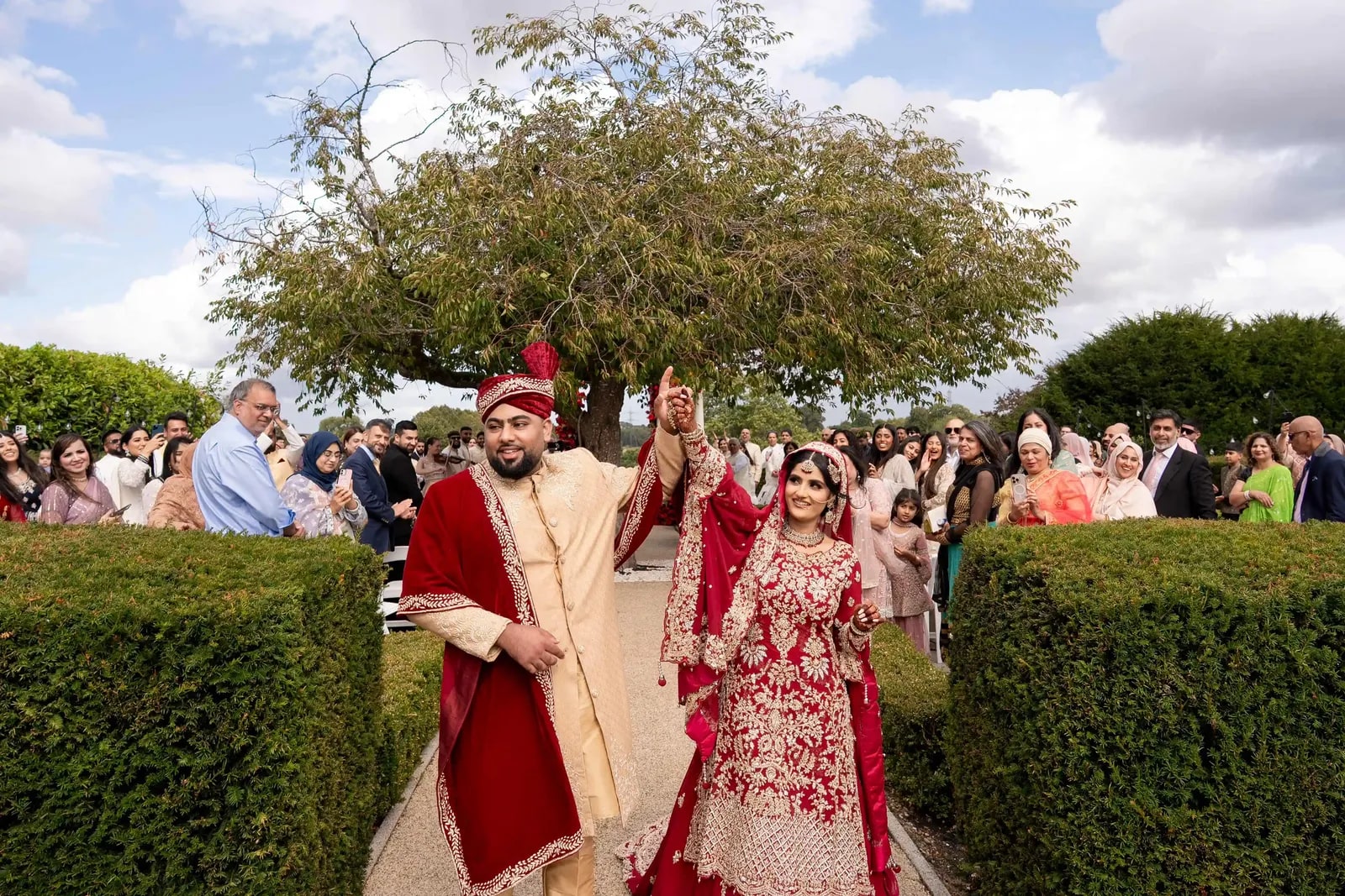 Bride and groom walking out with their arms raised, guests standing to either side