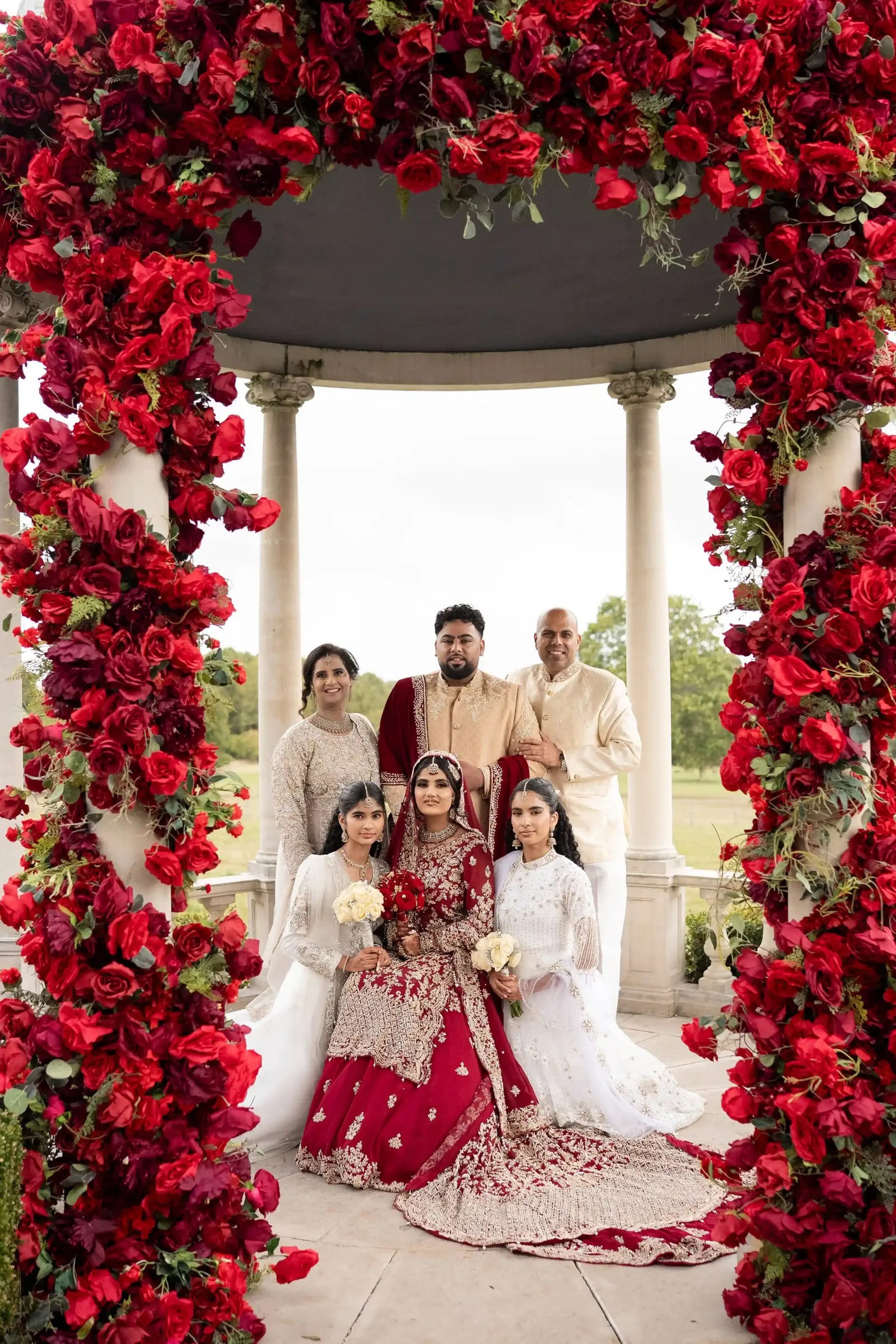 The bride's family posed with her beneath the red rose arch