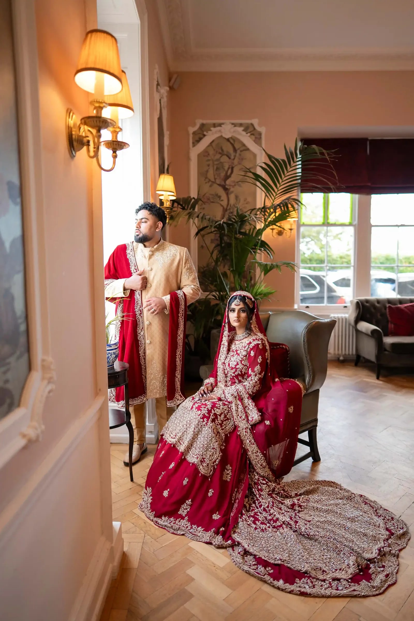 Bride seated in a panelled room, her crimson train spread across the parquet
