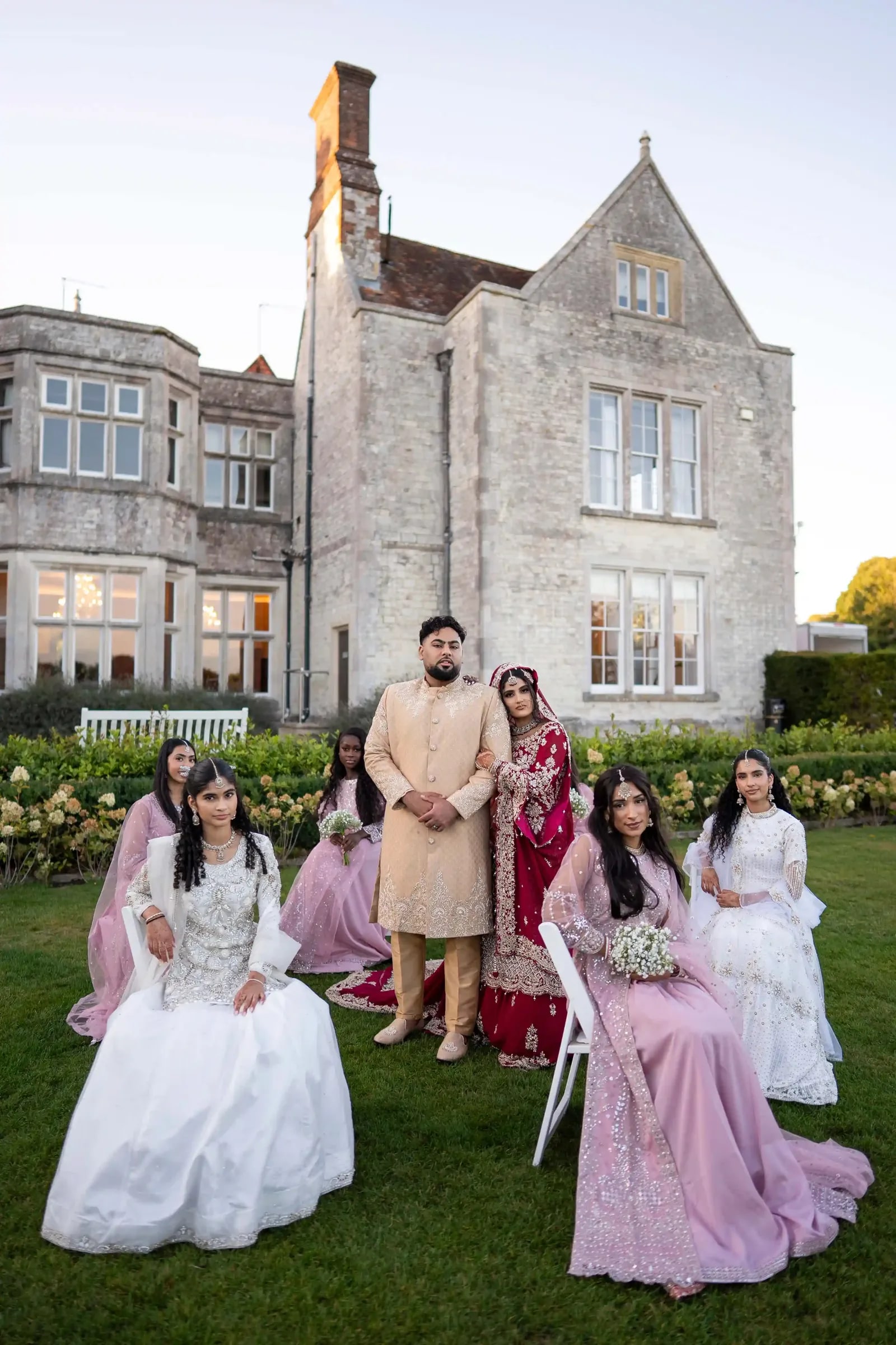 Groom standing with the bride and her party on the lawn in front of the house