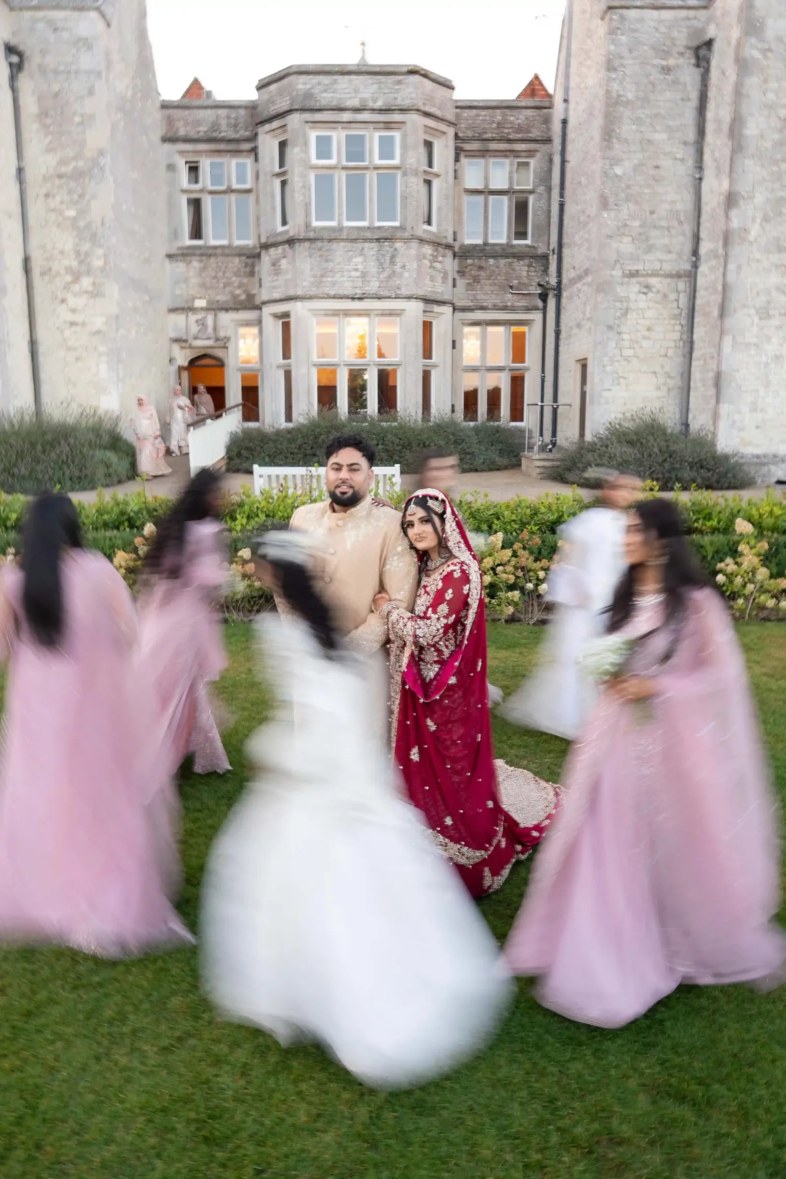 The couple still at the centre while the bridal party circles them, blurred with movement