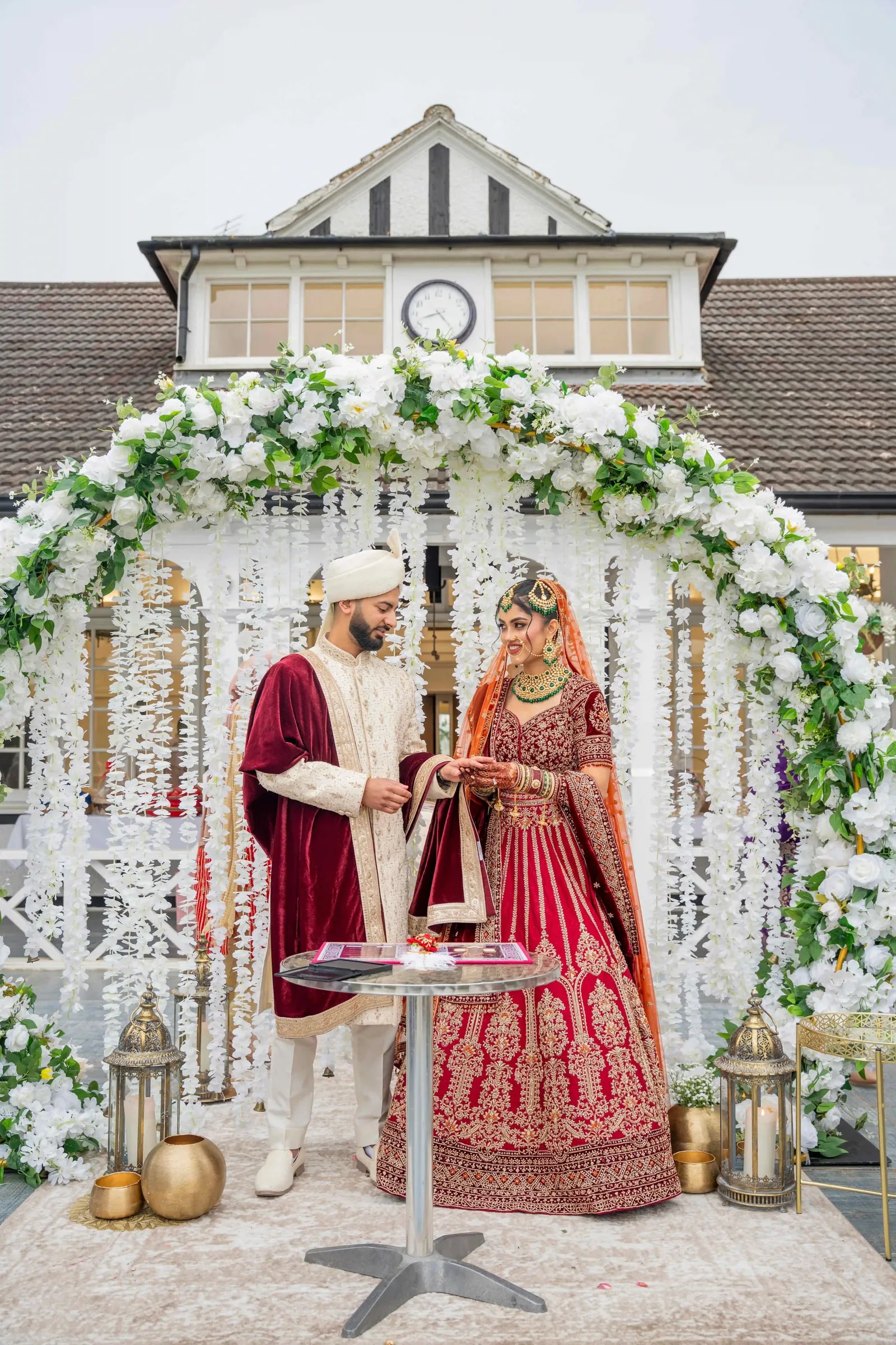Bride and groom signing the register beneath a white flower arch
