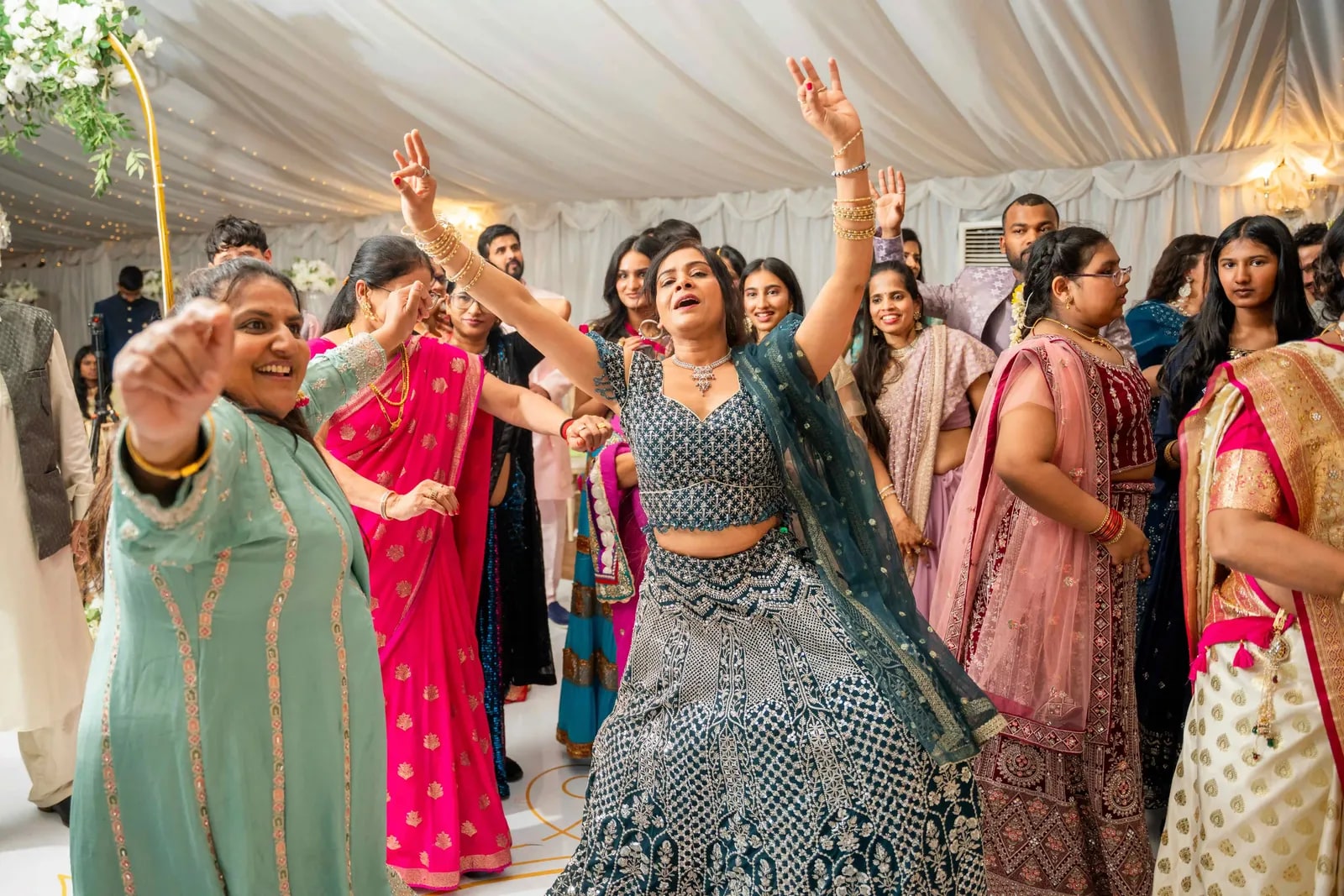 Women dancing together in the marquee with their arms in the air