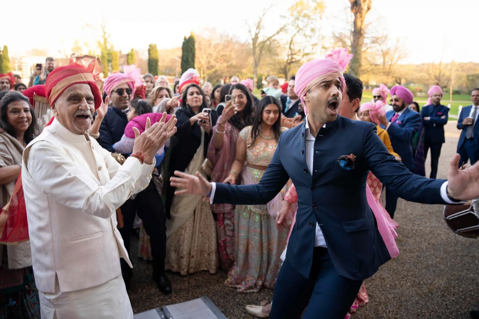 Guests in pink turbans dancing outside as the baraat arrives