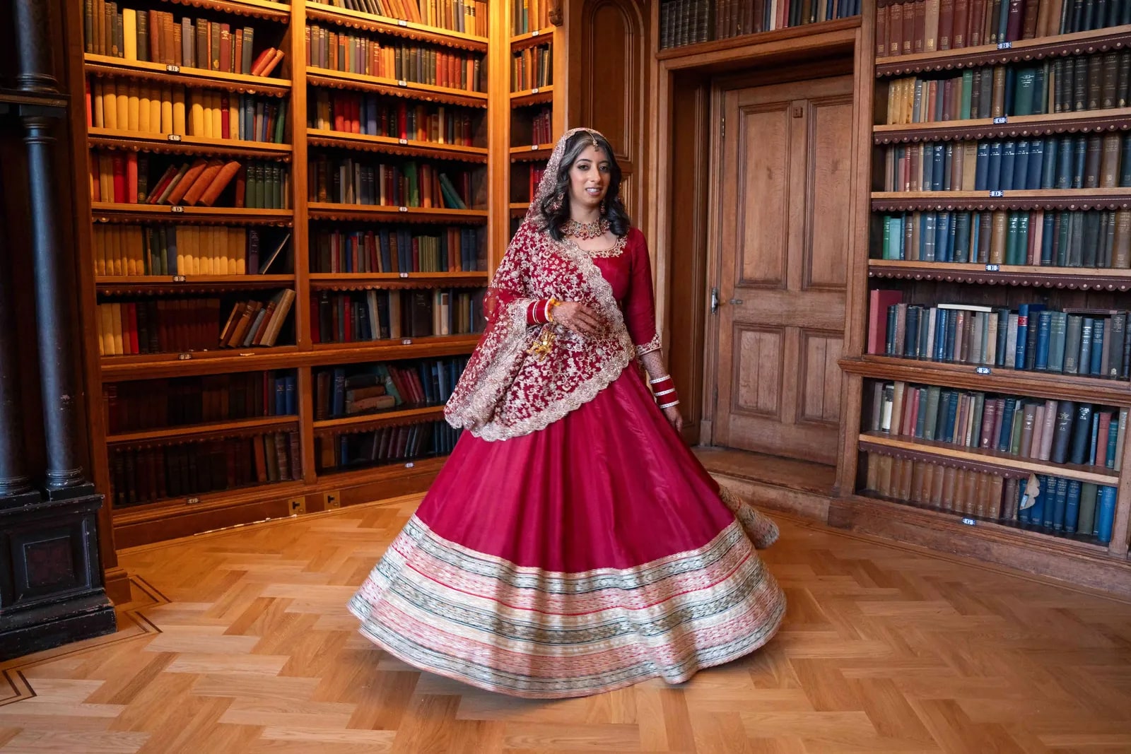 Bride alone in the panelled library in a deep pink lehenga