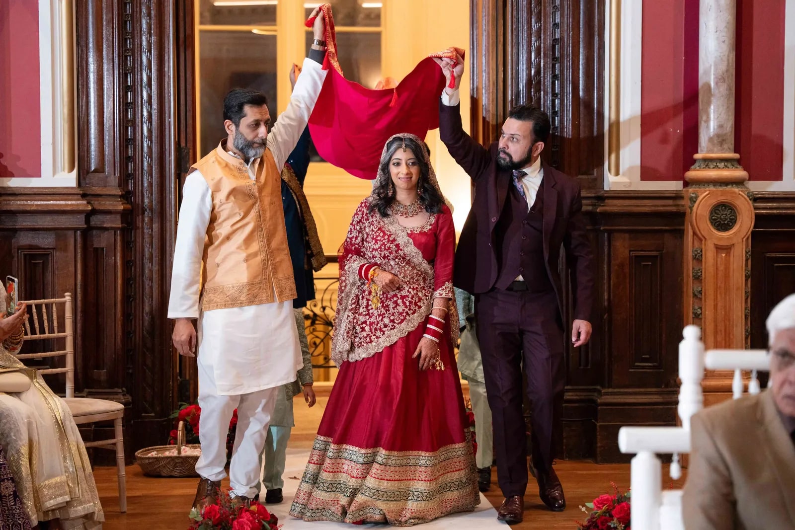 The bride walked in under a red cloth held up by two of her family