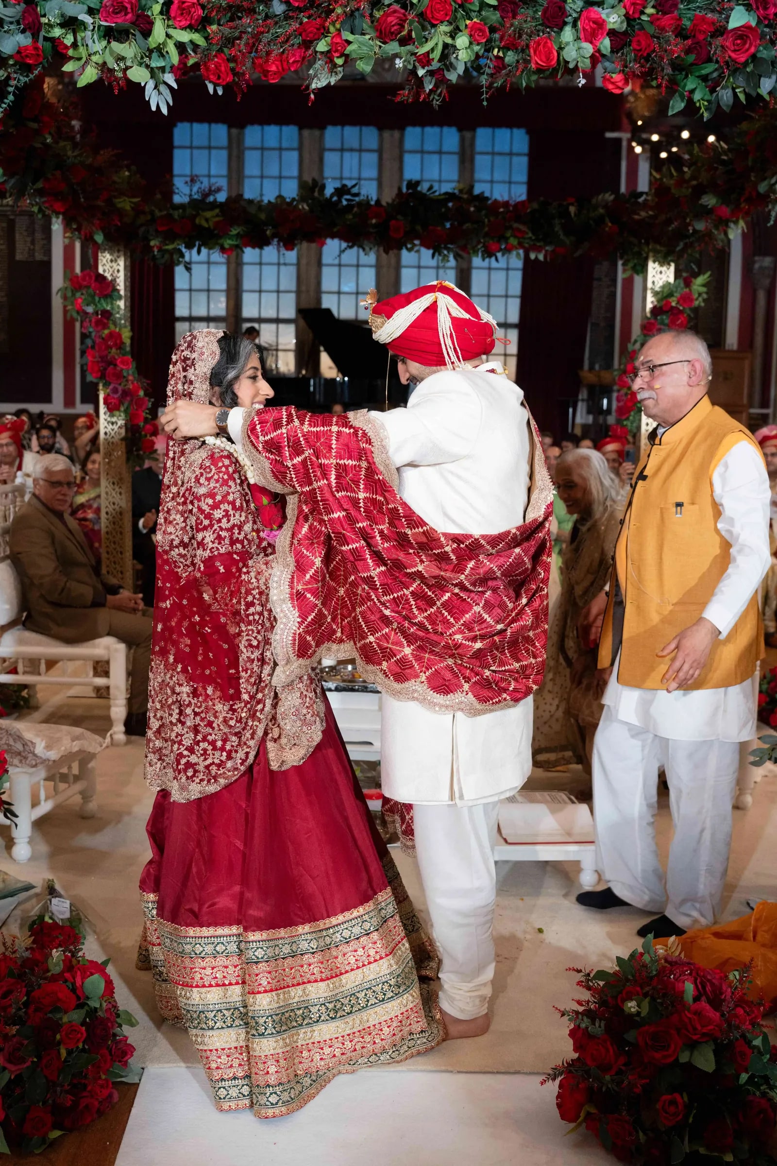 Groom reaching to place the garland over his bride during the jaimala
