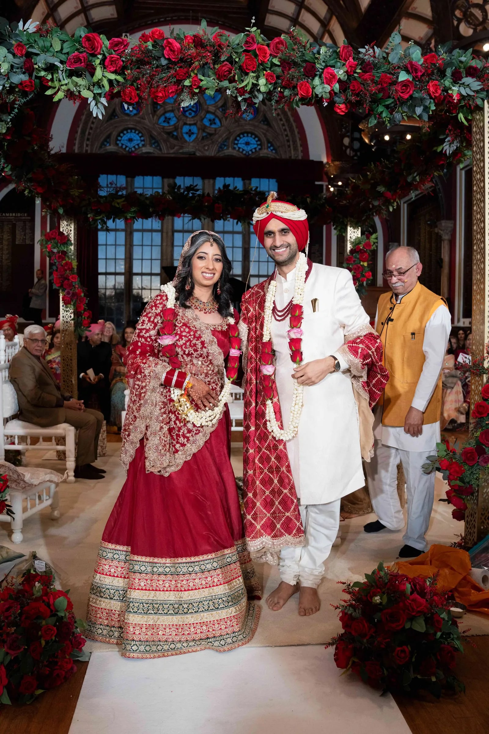 Bride and groom standing garlanded at the mandap, guests seated around