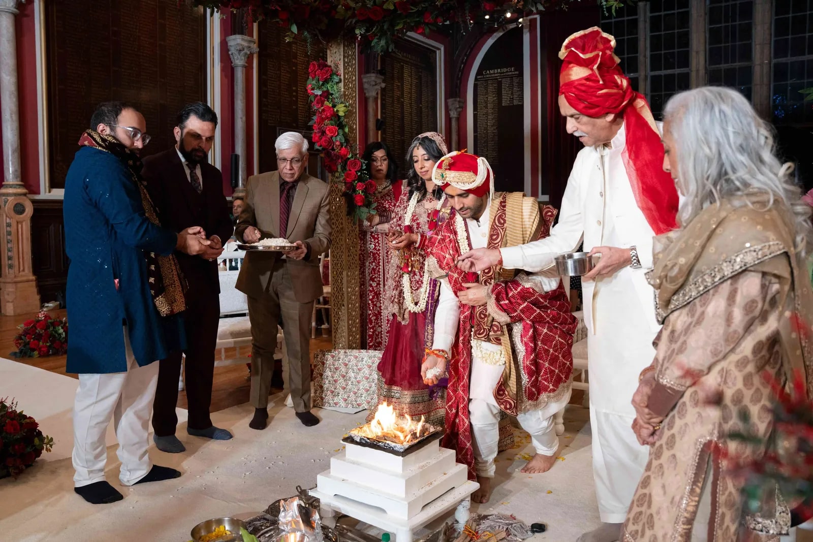 The couple making offerings into the sacred fire, the priest and family beside them