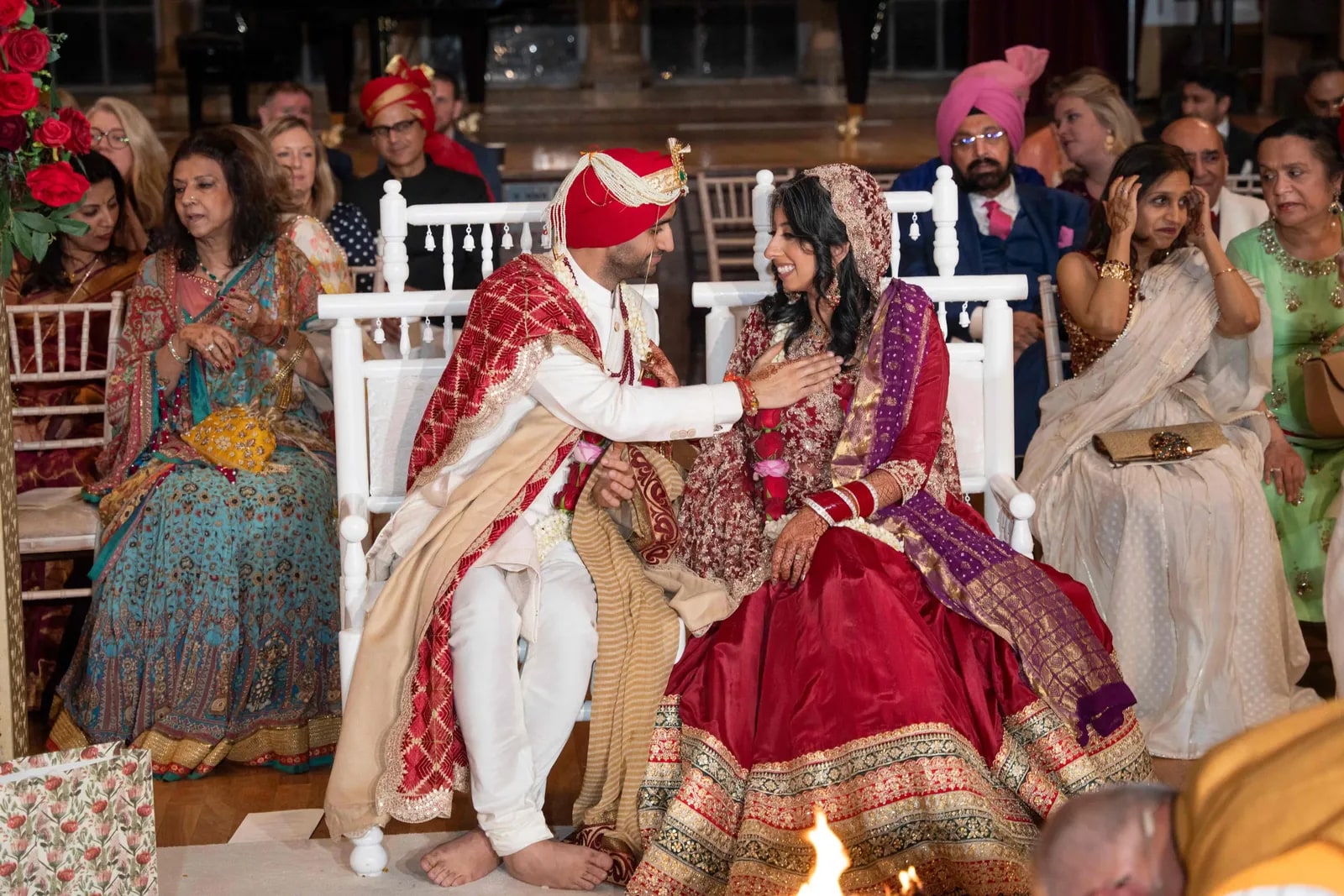 Groom applying the sindoor to his bride, seated together beside the fire
