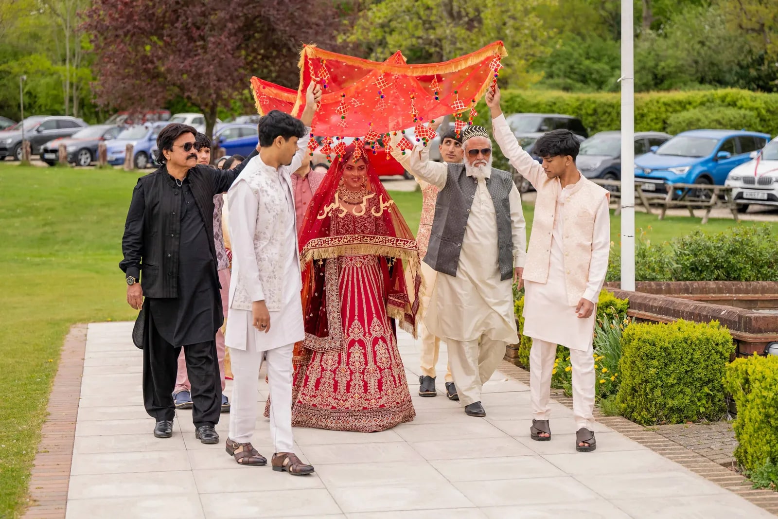 The bride's family carrying the cloth canopy over her along the path