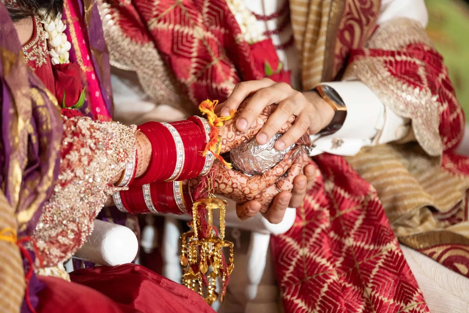 The couple's hands joined over the offering, hers hennaed and in red chura