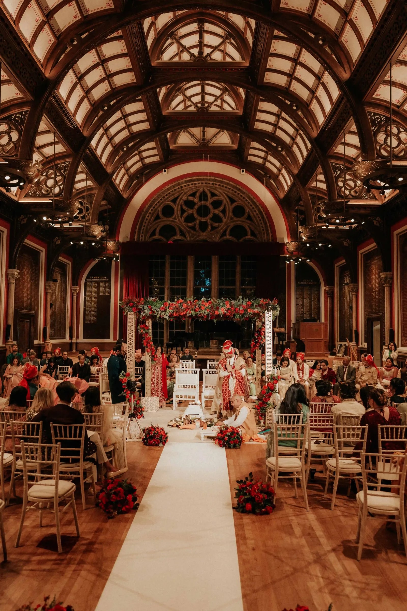 The vaulted timber hall at Dulwich College set for the ceremony, red flowers down the aisle