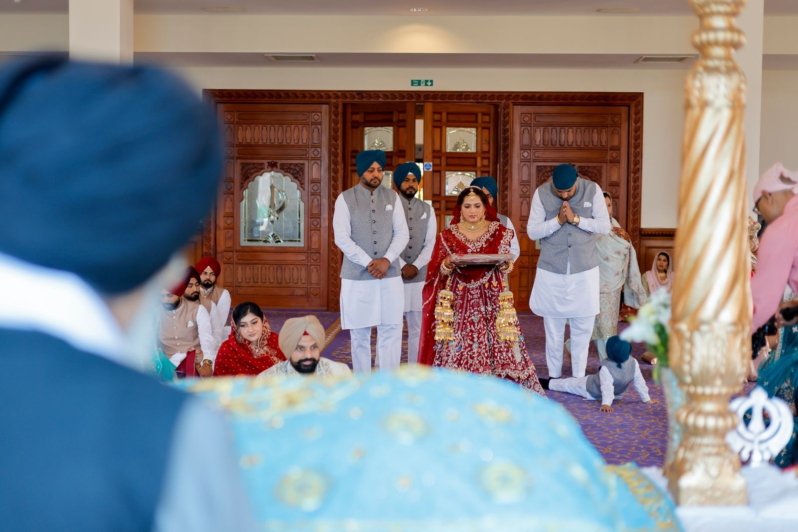 The couple seen past a guest's shoulder as they stand in the gurdwara
