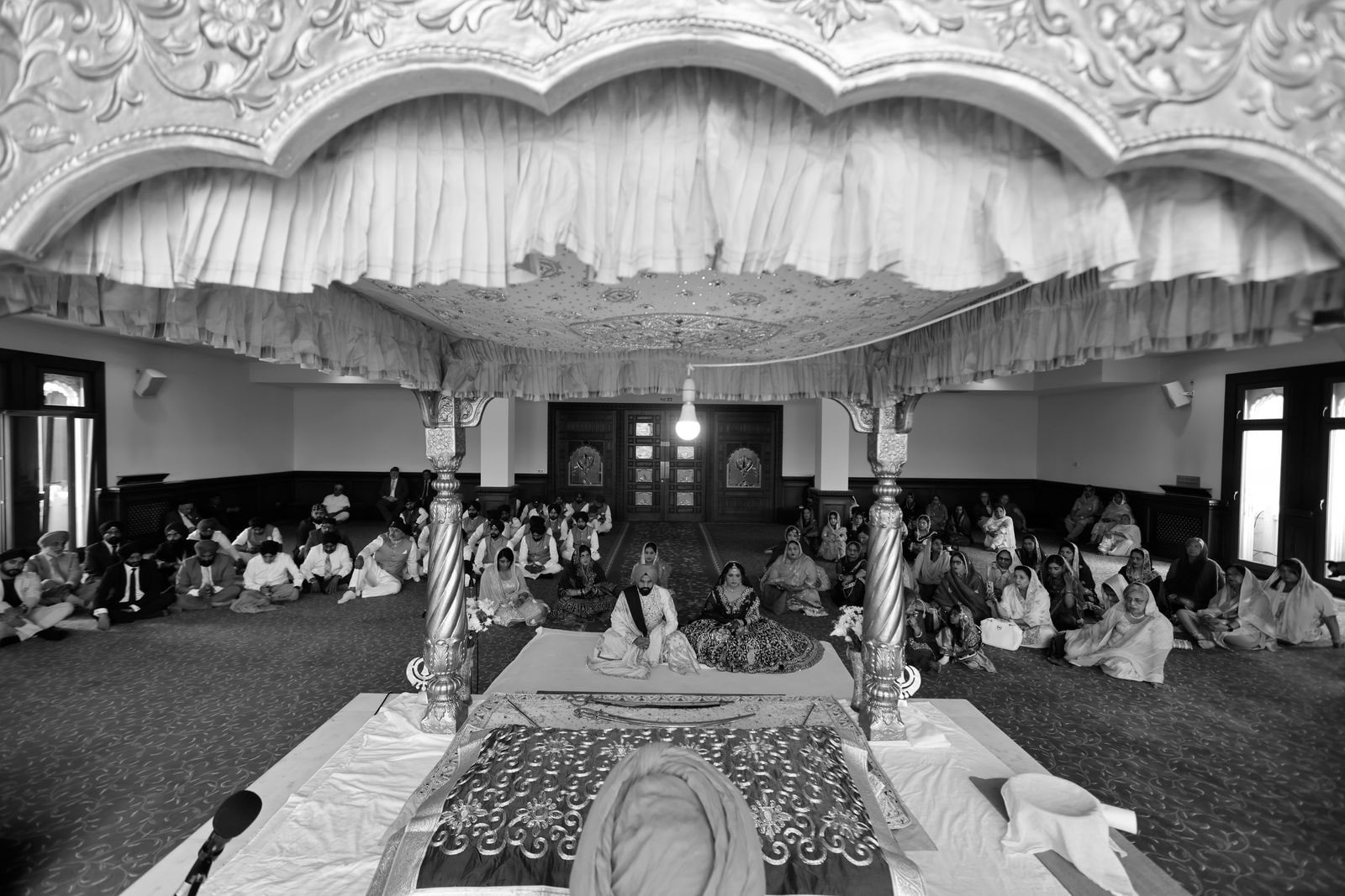 The palki and canopy in the gurdwara with the congregation seated, in black and white