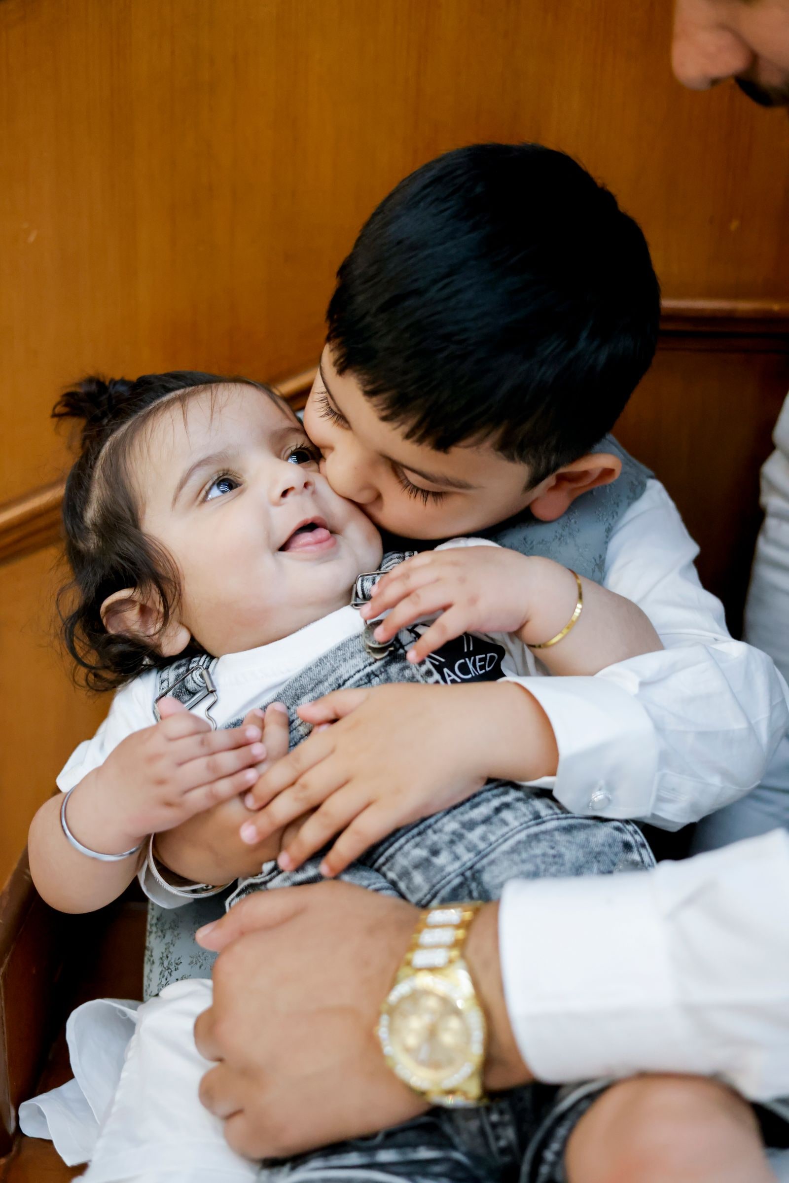 A boy kissing a baby on the cheek at the reception