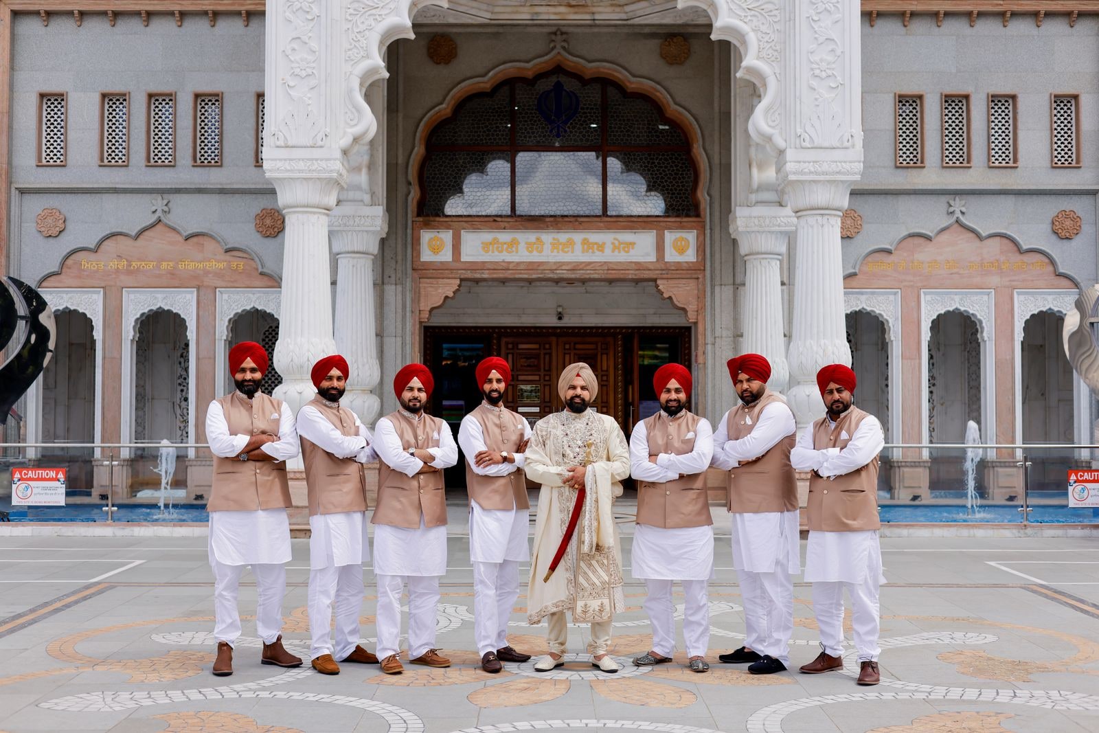 Groom and his party in red turbans lined up outside the white marble gurdwara