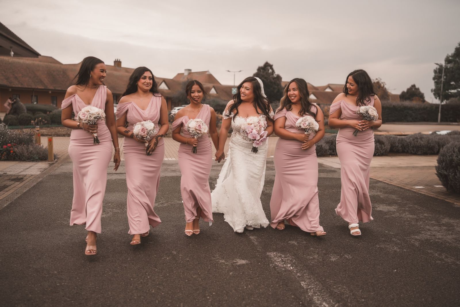 The bride walking with her six bridesmaids in pink, all carrying bouquets
