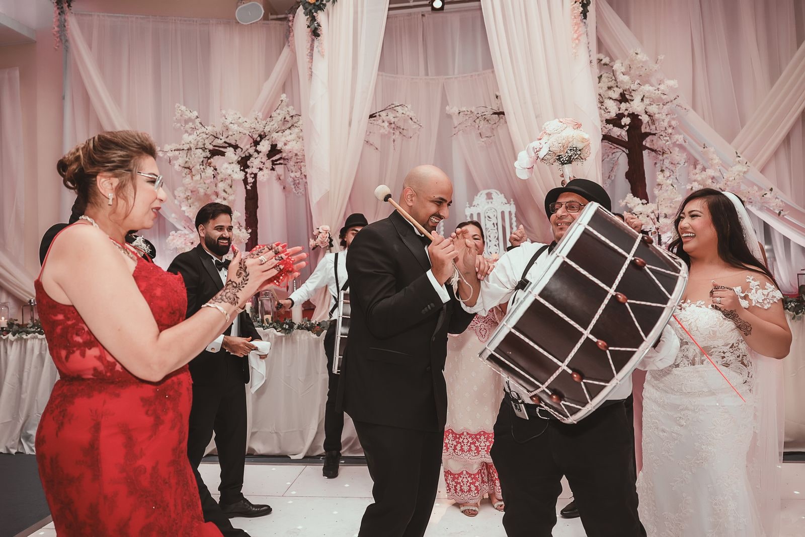 Dhol players drumming for the couple as guests dance around them