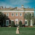 Bride and groom arriving by vintage wedding car at a grand London wedding venue with their wedding photographer and videographer in london