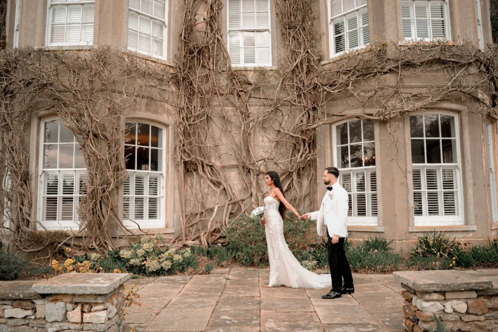 Hindu bride and groom walking through garden grounds of London wedding venue for asian wedding photography and videography prices guide