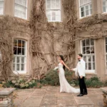 Hindu bride and groom walking through garden grounds of London wedding venue for asian wedding photography and videography prices London guide