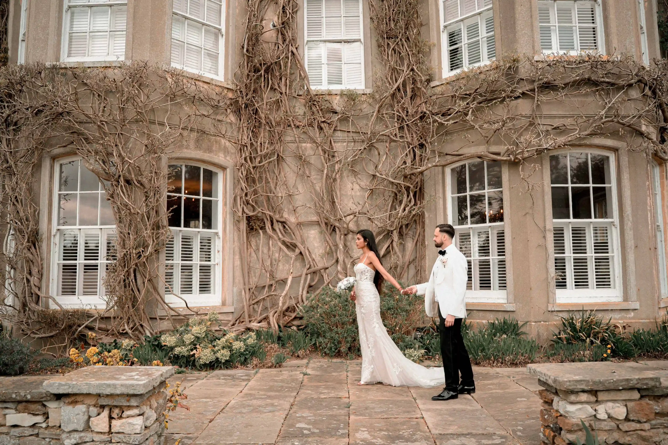 Hindu bride and groom walking through garden grounds of London wedding venue