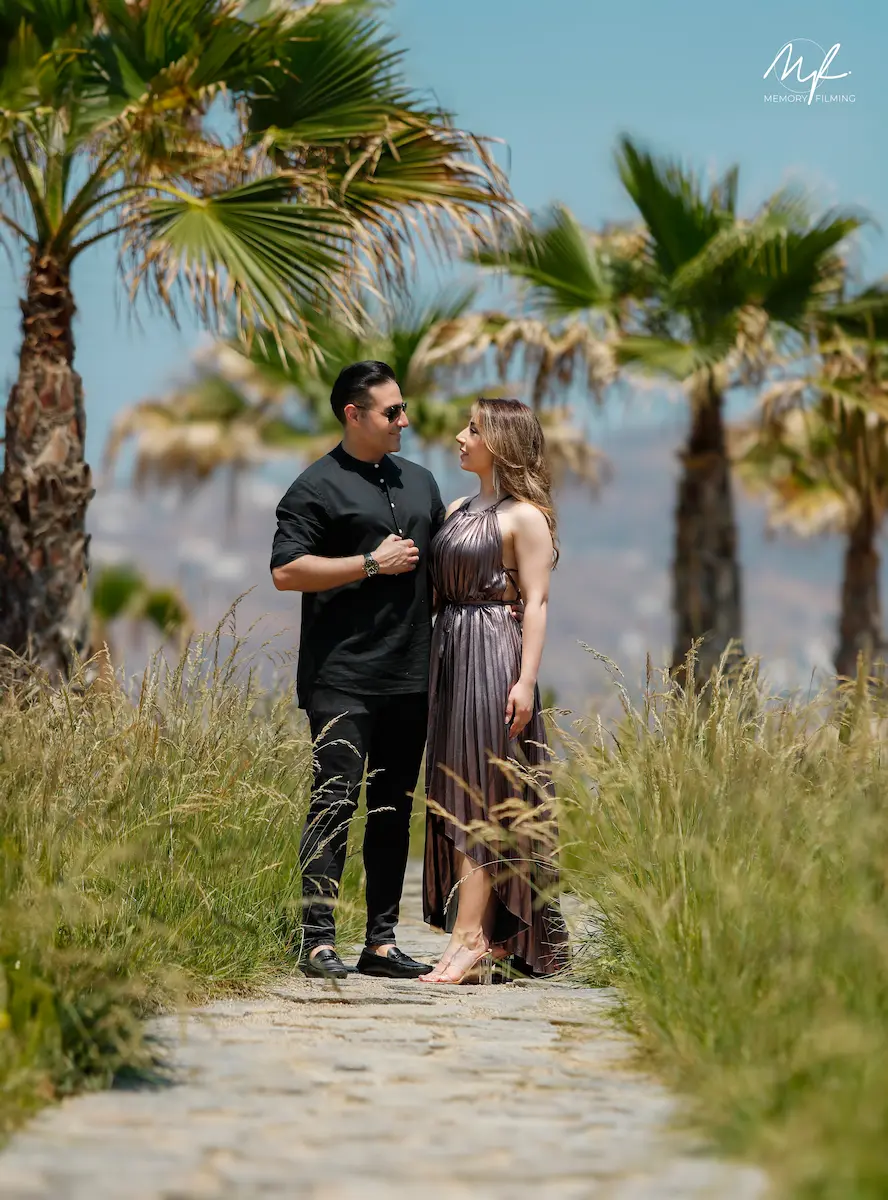 Couple standing together under tropical palm trees during a destination pre-wedding photoshoot