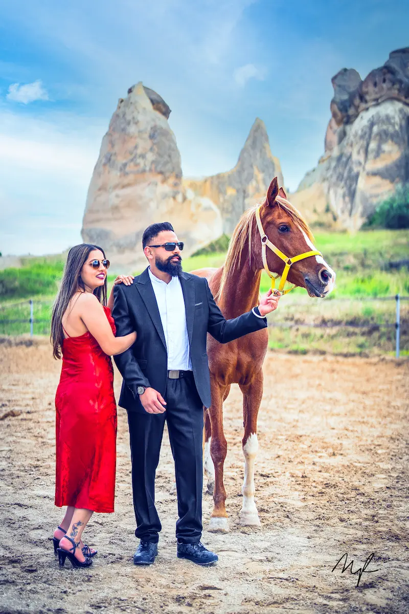 Couple posing with a horse against the fairy chimney rock formations in Cappadocia Turkey during a destination shoot