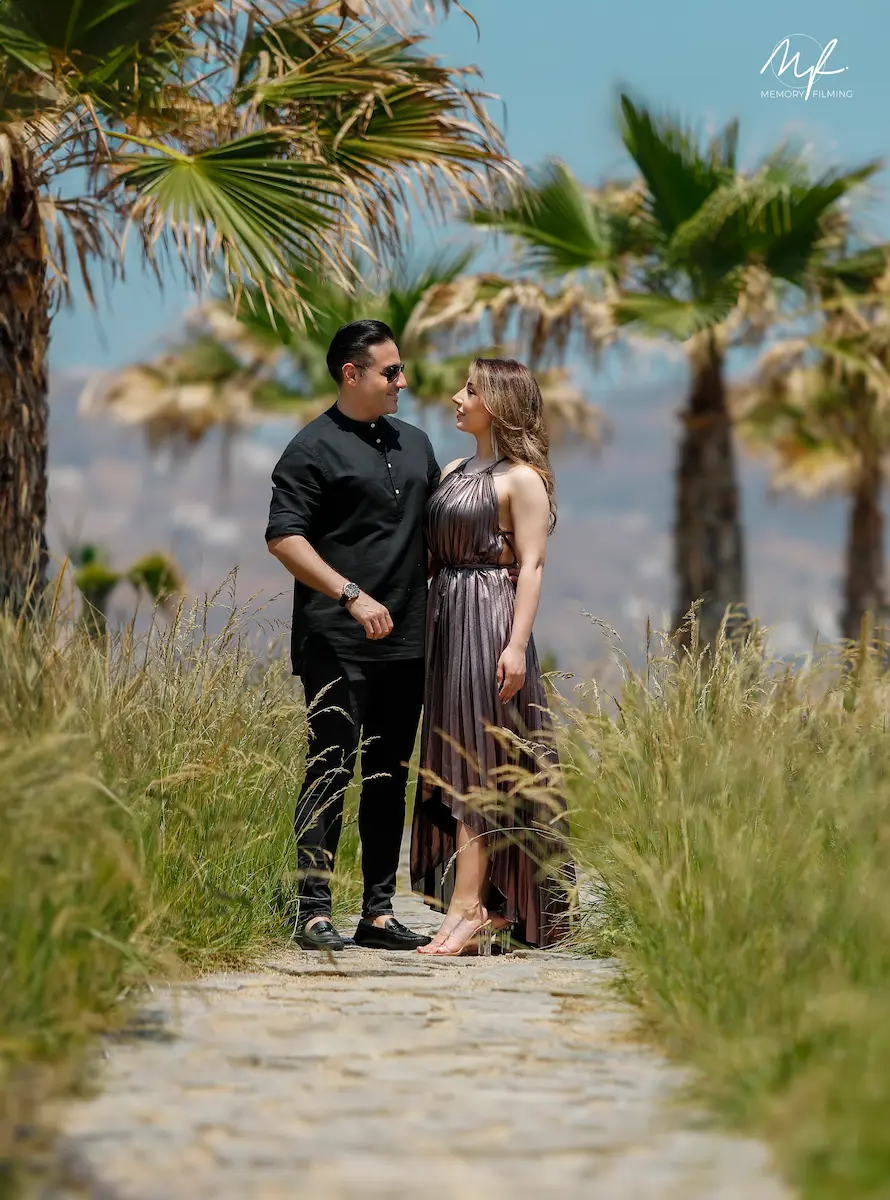 Couple gazing at each other on a paved stone pathway lined with palm trees during a tropical destination shoot