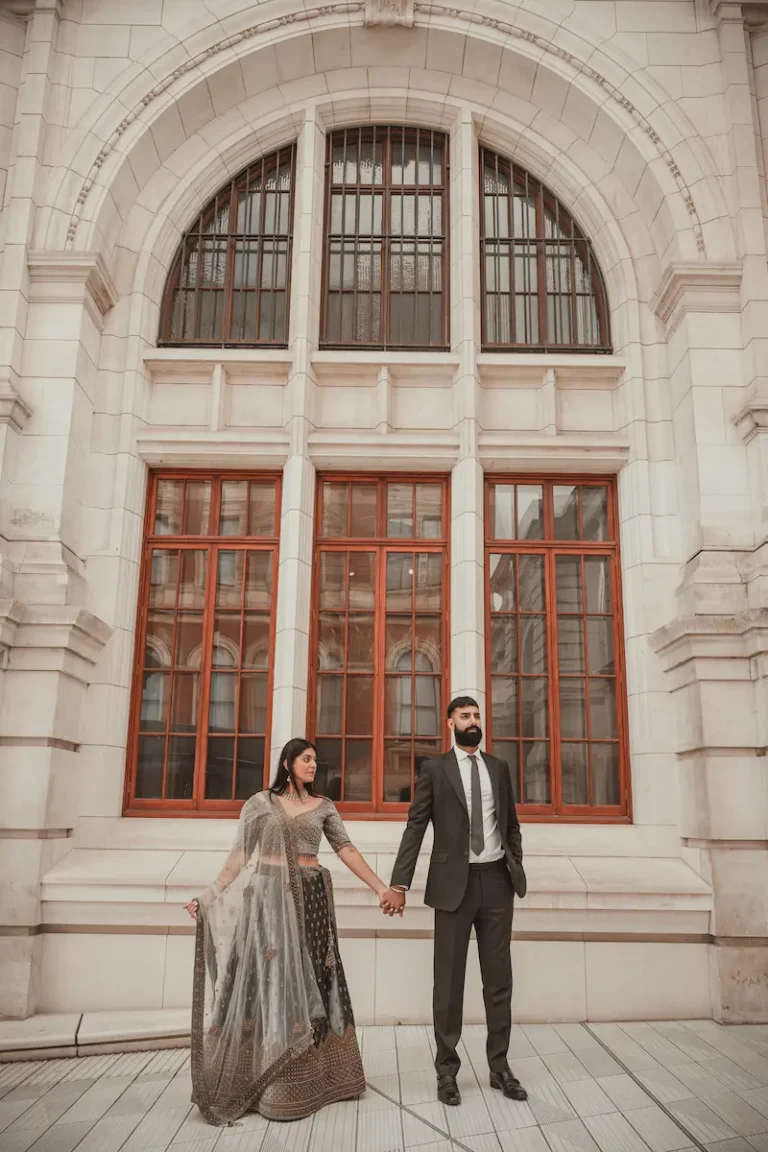 Couple holding hands during a pre-wedding photoshoot outside historic grand architecture in London